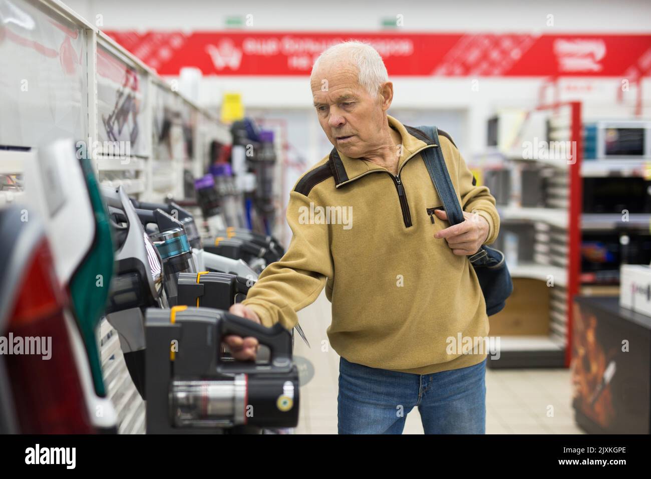 elderly man choosing Upright Vacuum hoover in showroom of electrical appliance store Stock Photo
