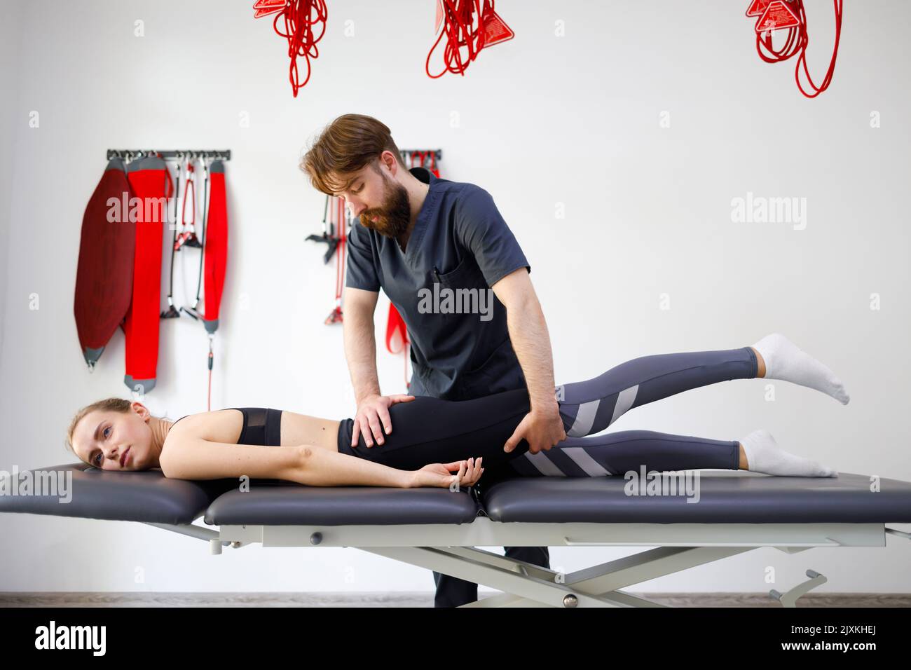 Chiropractor stretching the legs and hips of a young female patient. Diagnosis of diseases of the lumbar disc Stock Photo