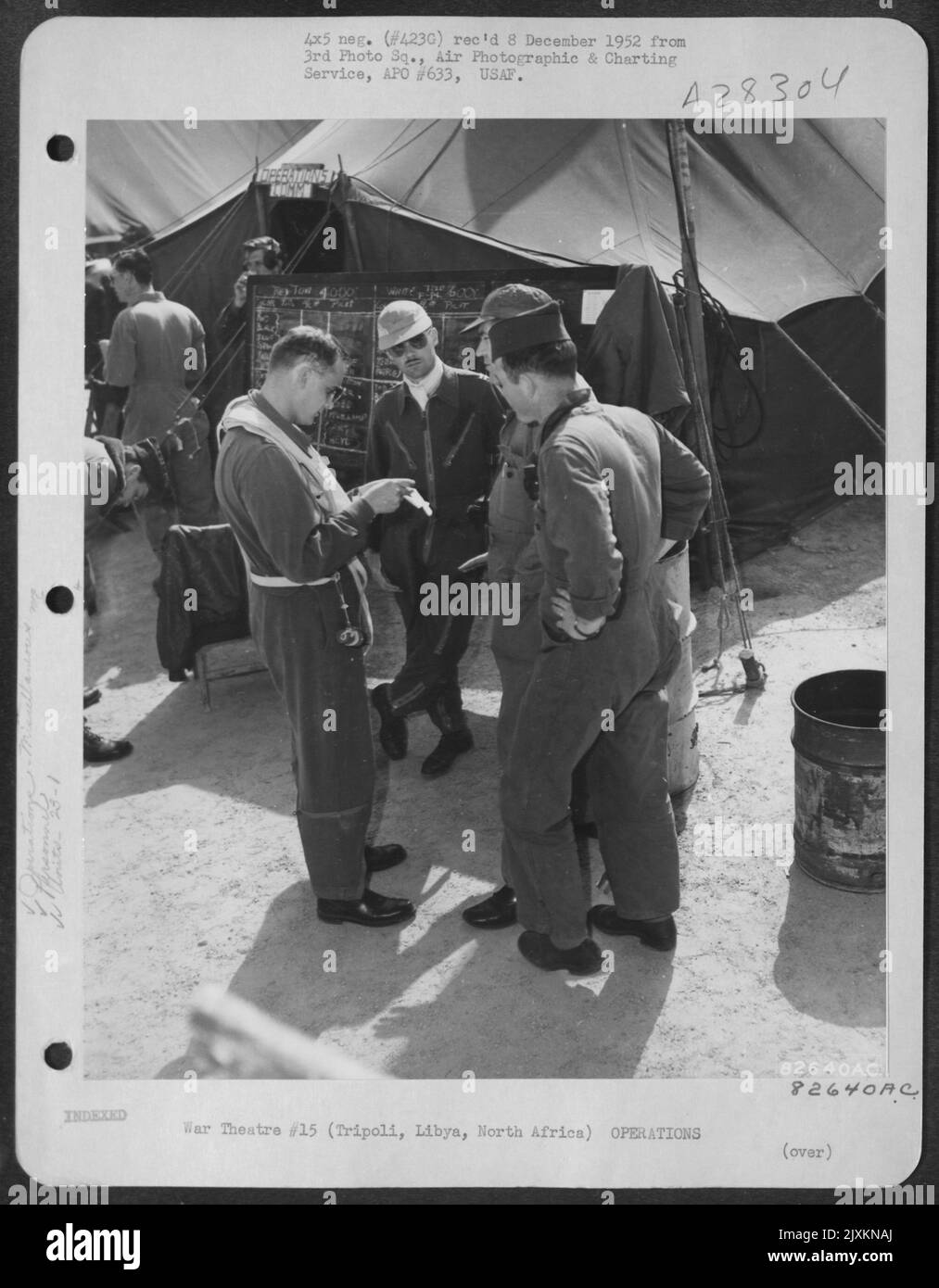 Lt. Col. Marvin E. Childs, commanding officer of the 23rd Fighter Bomber Squadron and Capt. Cobb, engineering officer, read over script with M/Sgt. Anderson and S/Sgt. Toole, cameramen of the 1st Photo Squadron for the filming of their gunnery Stock Photo
