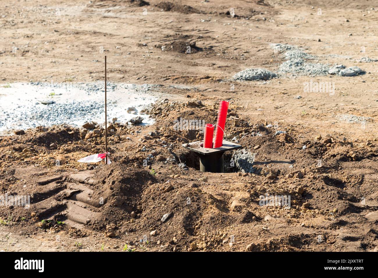 A red plastic pipe sticking out of the ground is an irrigation system