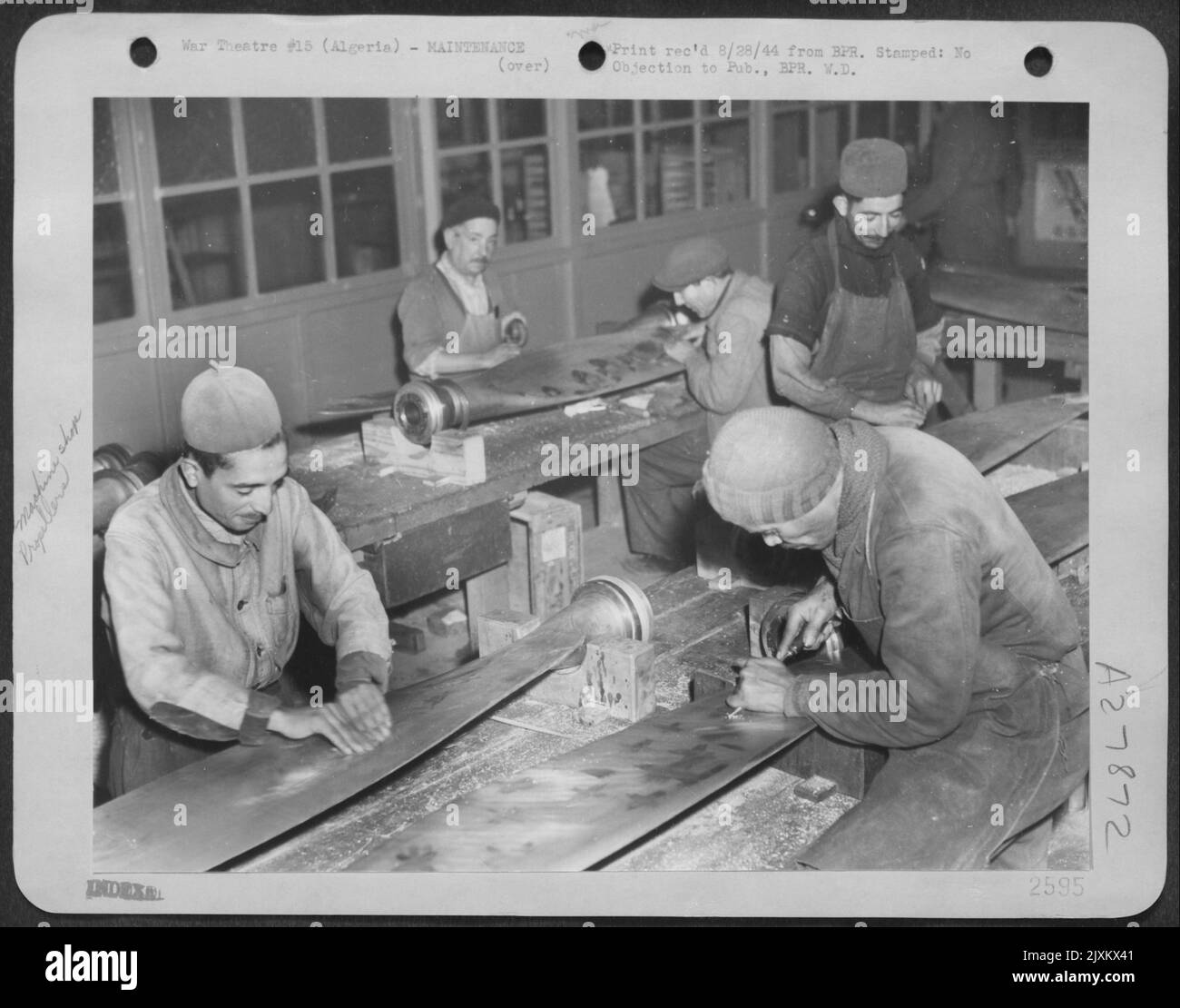 PROPELLER SHOP. Native workmen identified by their red skull caps remove nicks from damaged