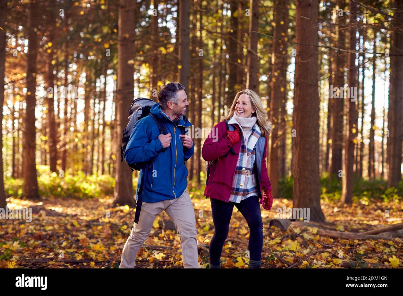 Mature Retired Couple With Backpacks Walking Through Fall Or Winter Countryside Stock Photo