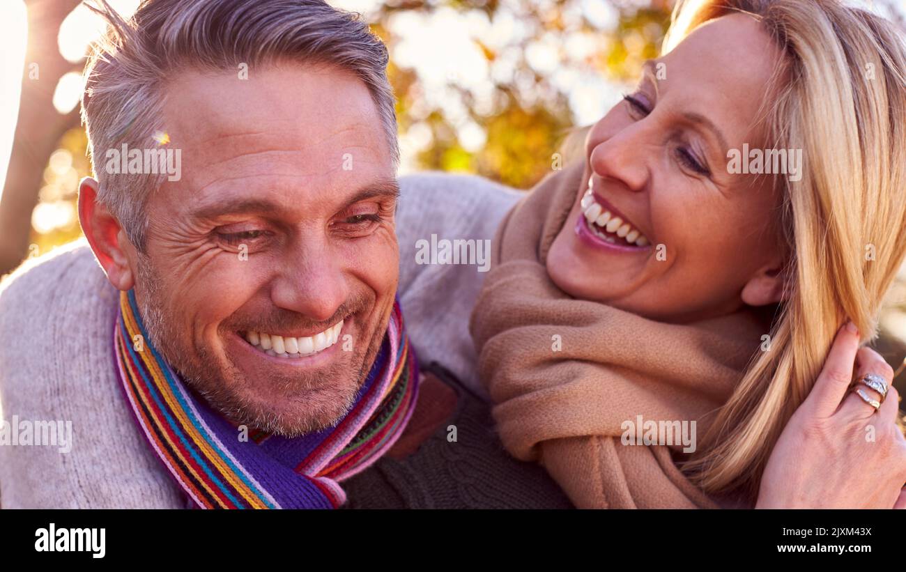 Loving Mature Woman Hugging Man From Behind As Retired Couple Walk Through Autumn Countryside Stock Photo