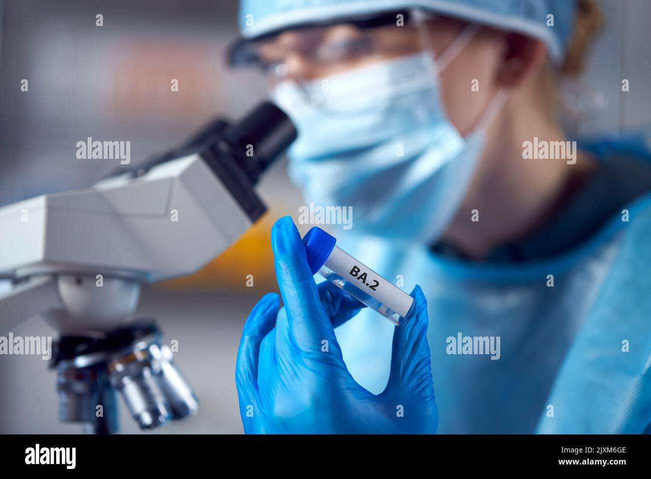 Female Lab Research Worker Wearing PPE Holding Test Tube Labelled BA.2 Stock Photo
