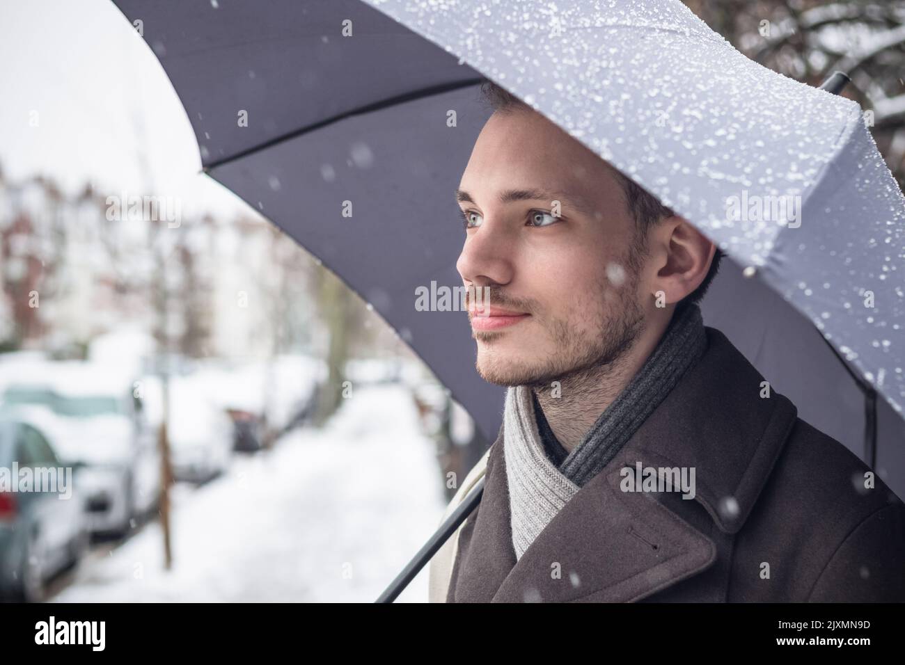 Portrait of a handsome young man with umbrella in winter snow Stock Photo