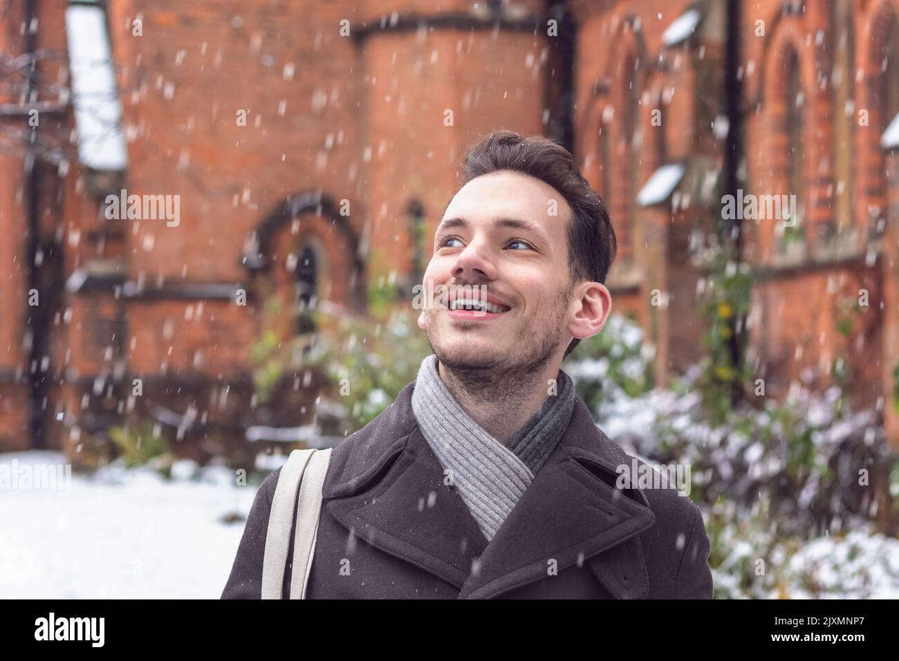 Portrait of a happy smiling man amazed by falling snow in winter Stock Photo