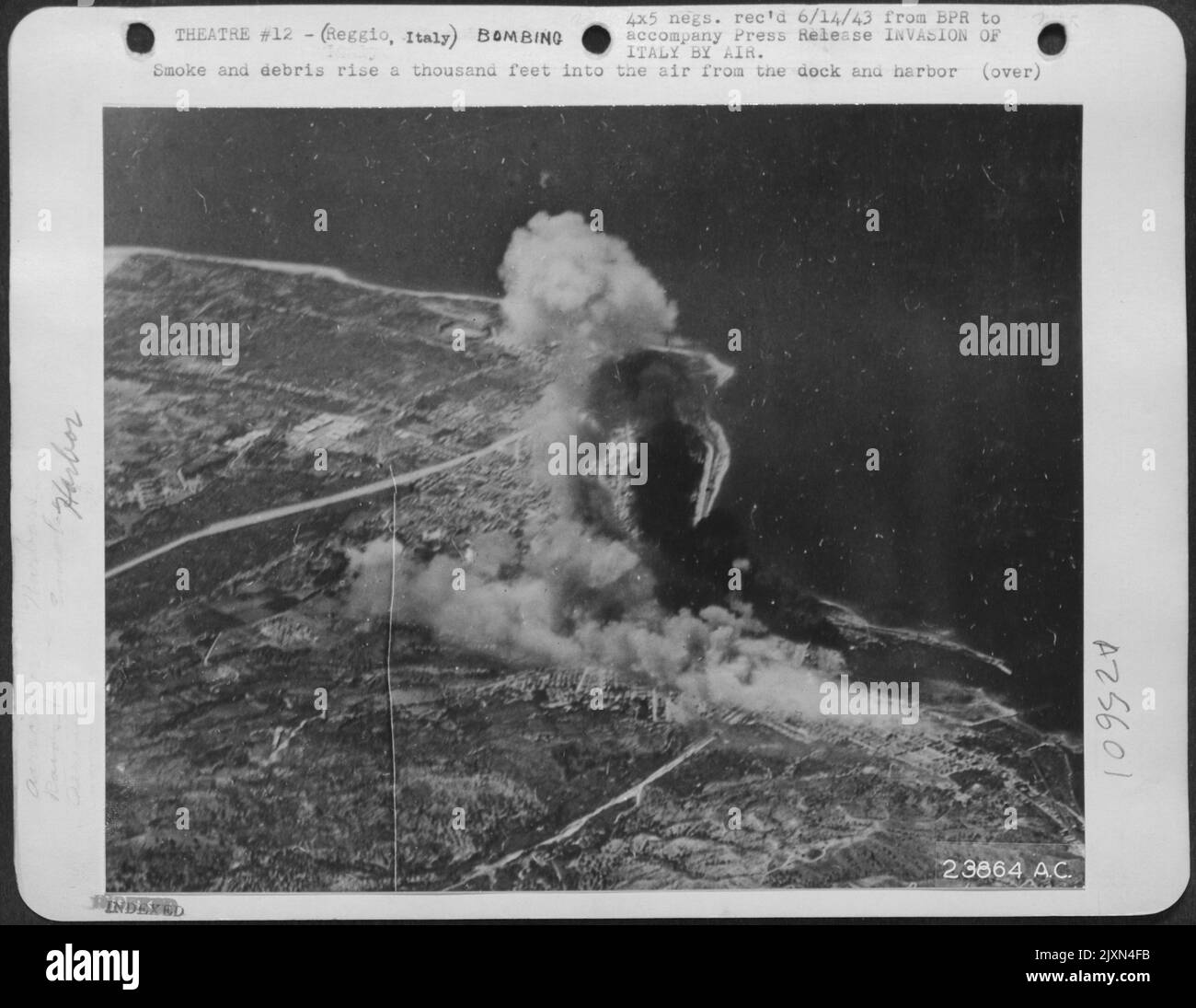 Smoke and debris rise a thousand feet into the air from the dock and harbor installations at Reggio, Italy, typifying the paralyzing blows being delivered today by American bombers. New attack technique of the United Nations is invasion by air, which Stock Photo
