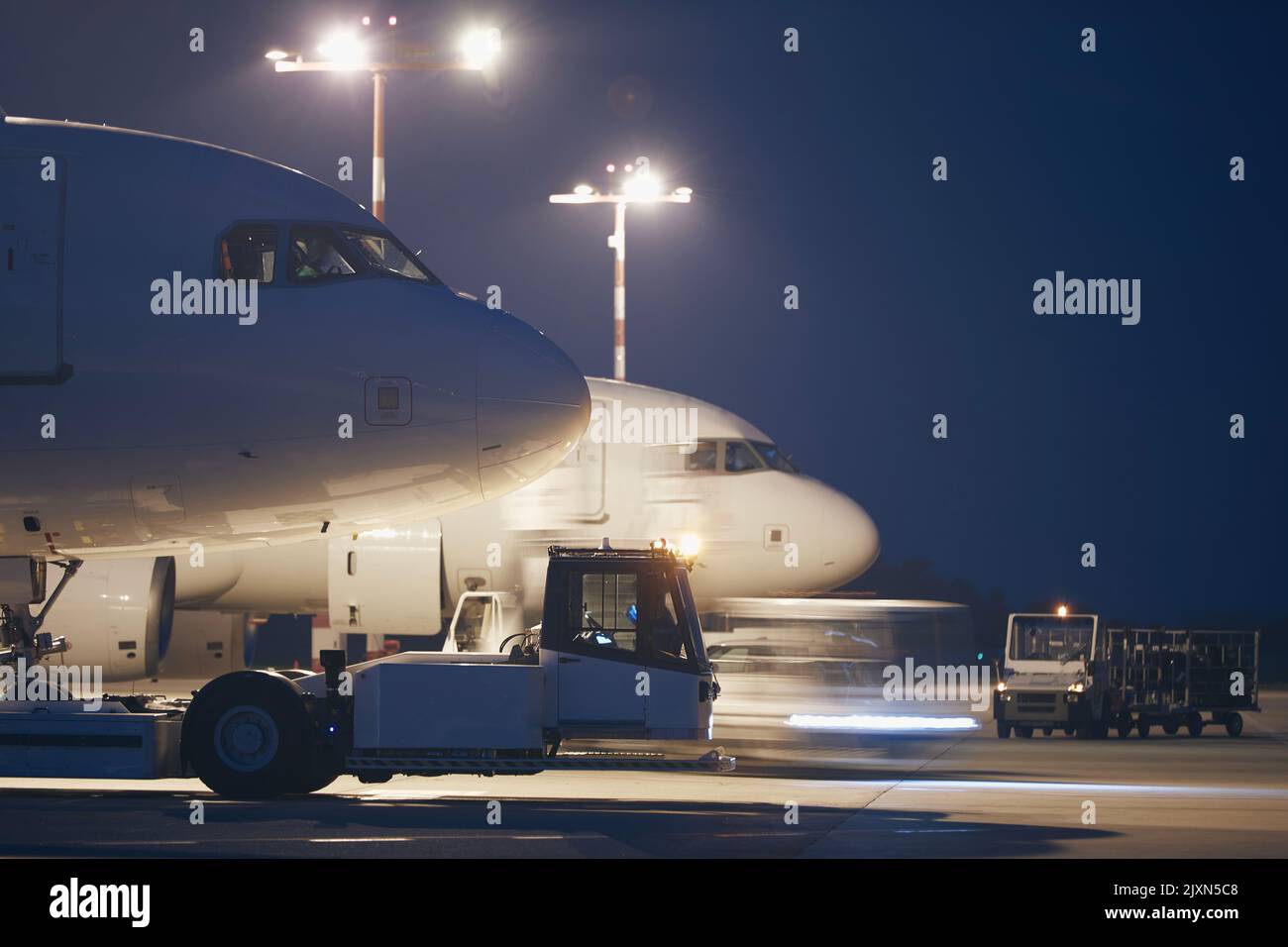 Busy airport at night. Preparation of airplanes before flight. Stock Photo