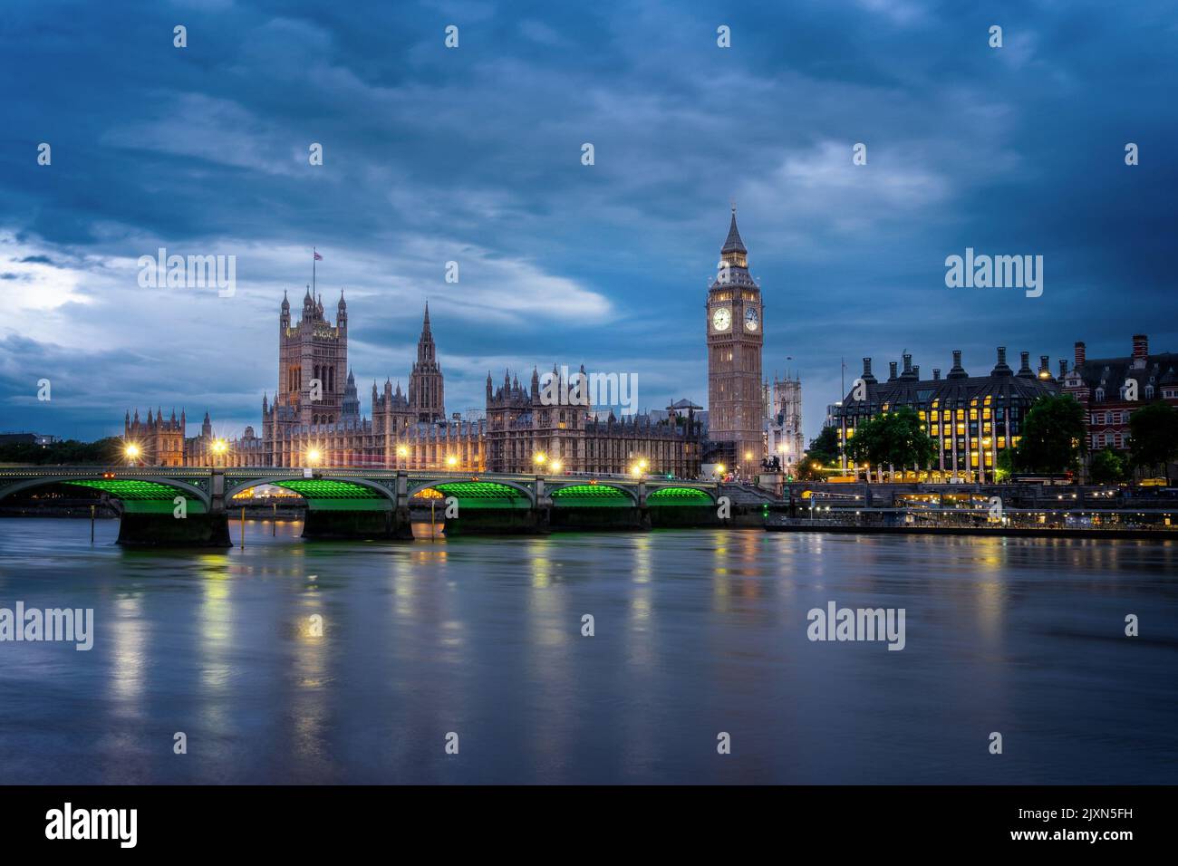 View of Westminster palace and bridge over river Thames with Big Ben illuminated at night in London, UK Stock Photo