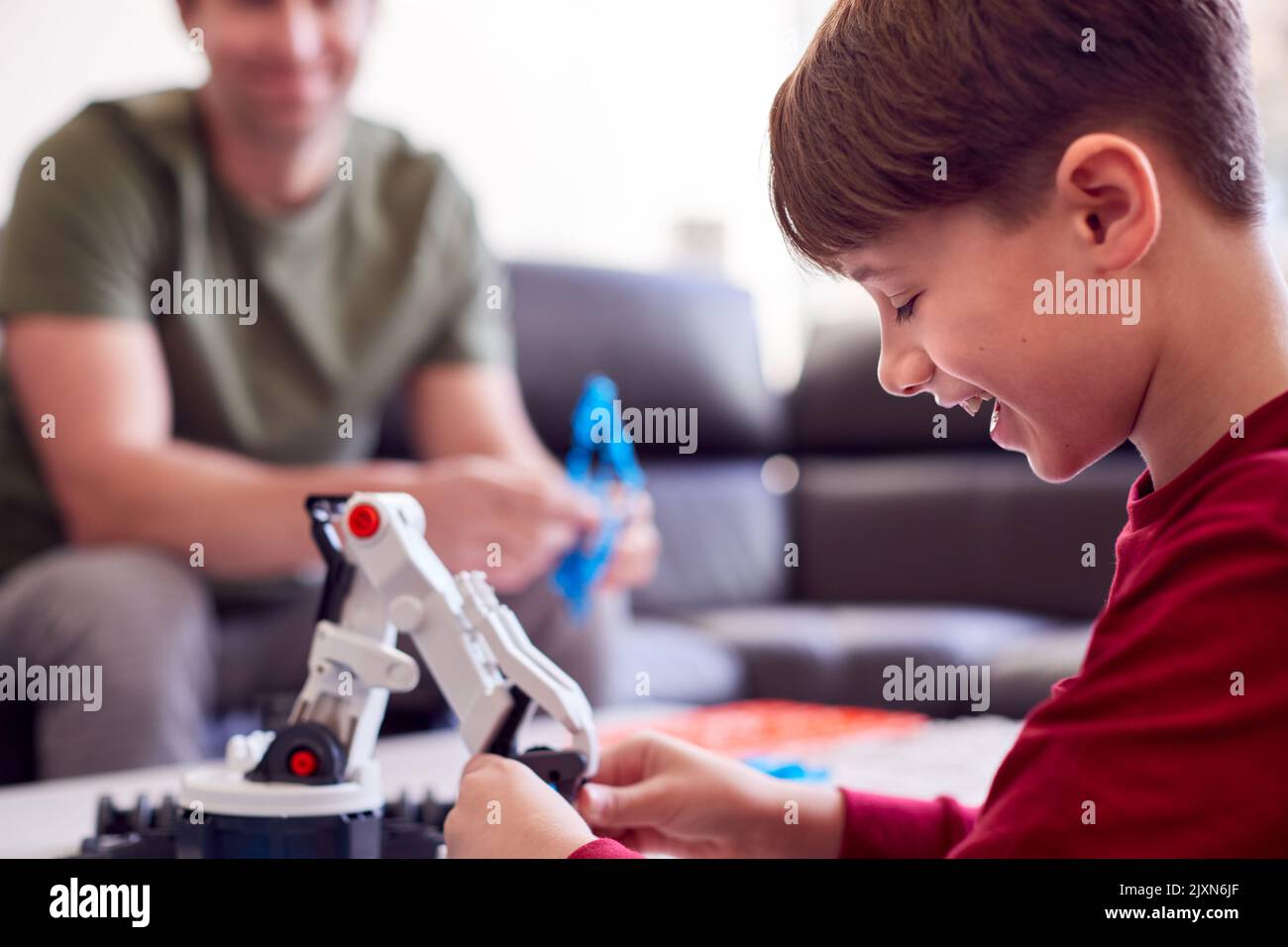 Father And Son Wearing Pyjamas Building Robotic Arm From Plastic Kit At Home Stock Photo