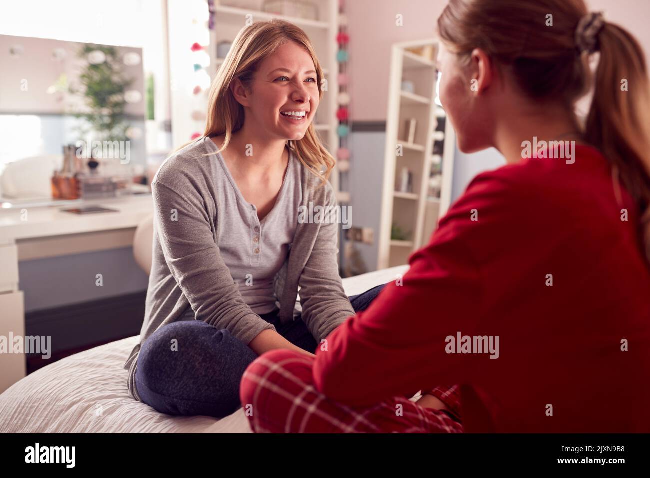 Teenage Daughter Wearing Pyjamas Sitting On Bed Talking To Mother In