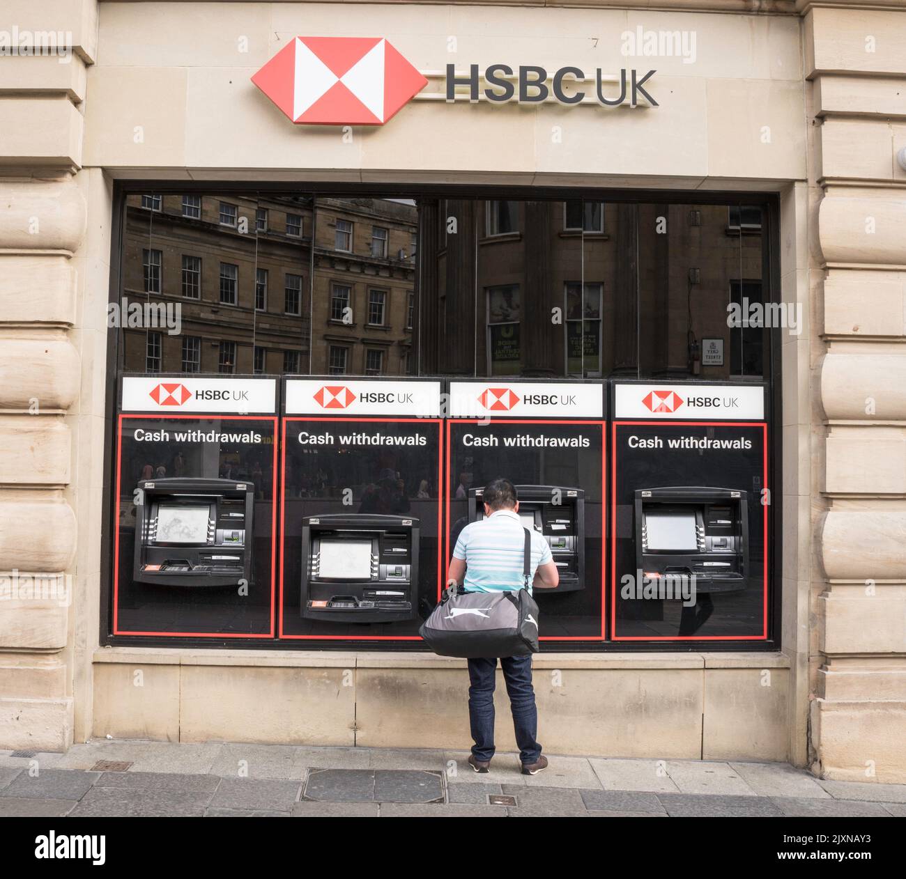 A man withdraws cash from an HSBC ATM in Newcastle upon Tyne, England, UK Stock Photo