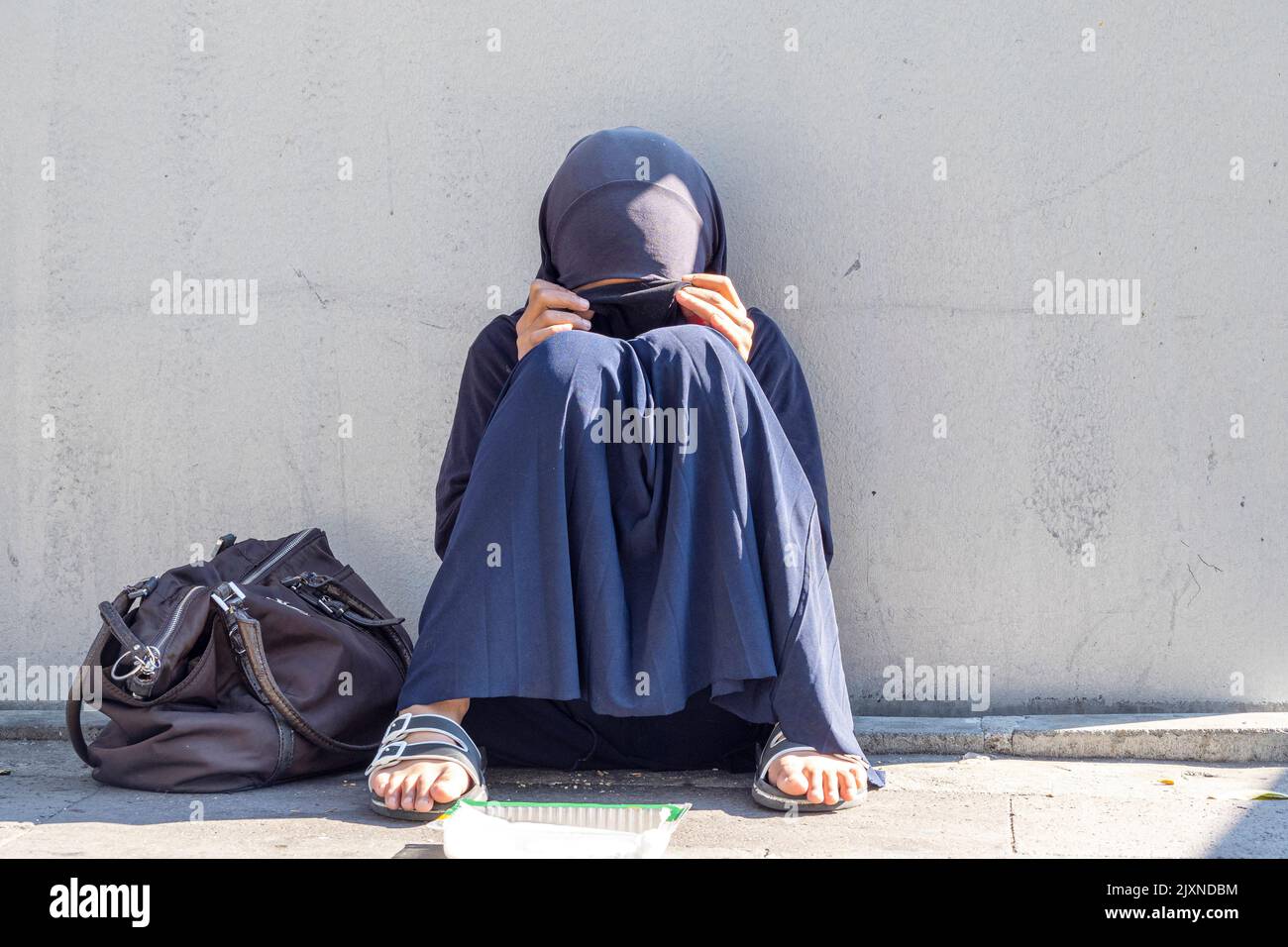 ISTANBUL - OCT 22: Muslim girl, woman sitting in a street of the city. Muslim woman with closed face begging for alms in Istanbul, October 22. 2021 in Stock Photo