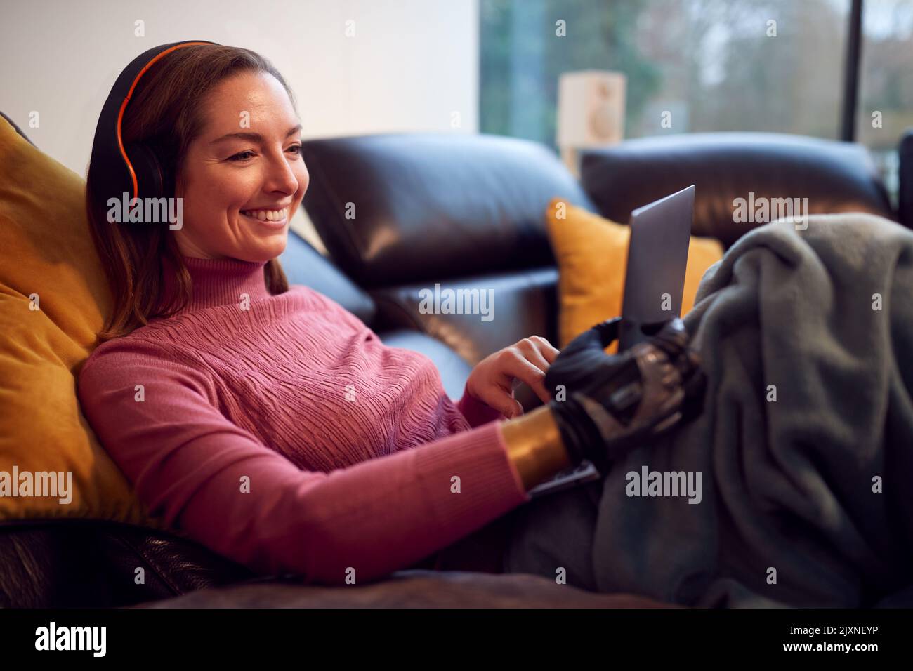 Woman With Prosthetic Arm Wearing Wireless Headphones And Watching