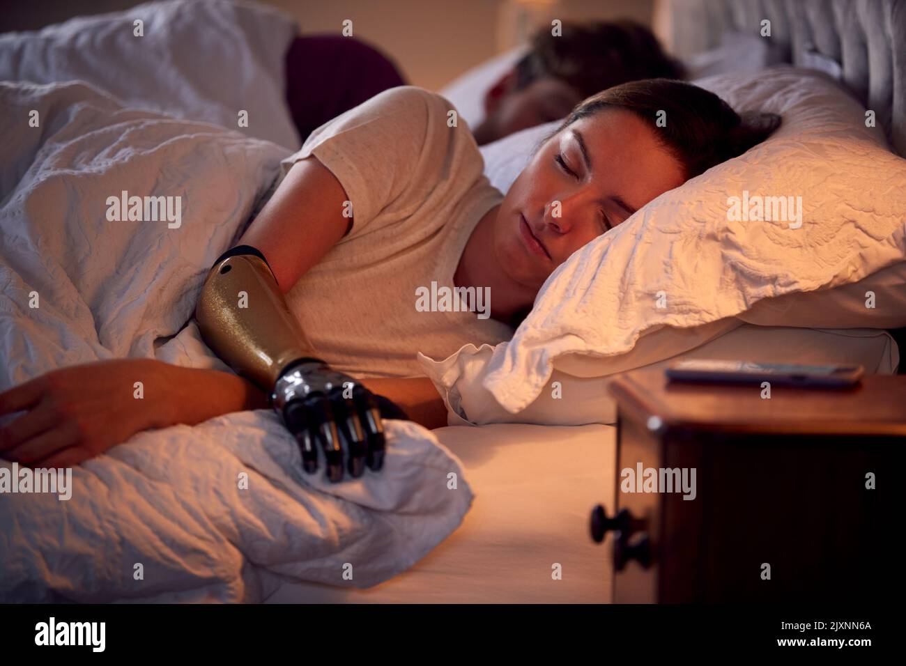 Couple With Woman With Prosthetic Arm Sleeping In Bed At Home Stock Photo