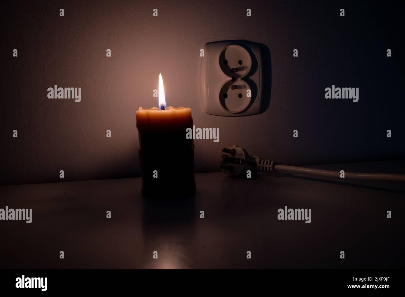 Blackout, candle with a socket, power cut - no electricity, the flame of a candle, circuit breaker, electrical outlet plug Stock Photo