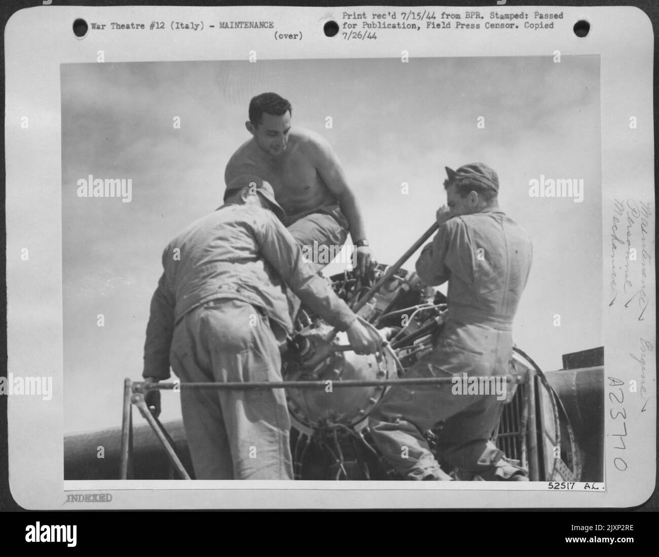 Men against the sky--are these three members of the Air Service Command as they prepare an airplane engine for installation of a re-conditioned propeller. The plane, a Consolidated B-24 Liberator, had made a crash landing on the shore of the Adriatic Stock Photo