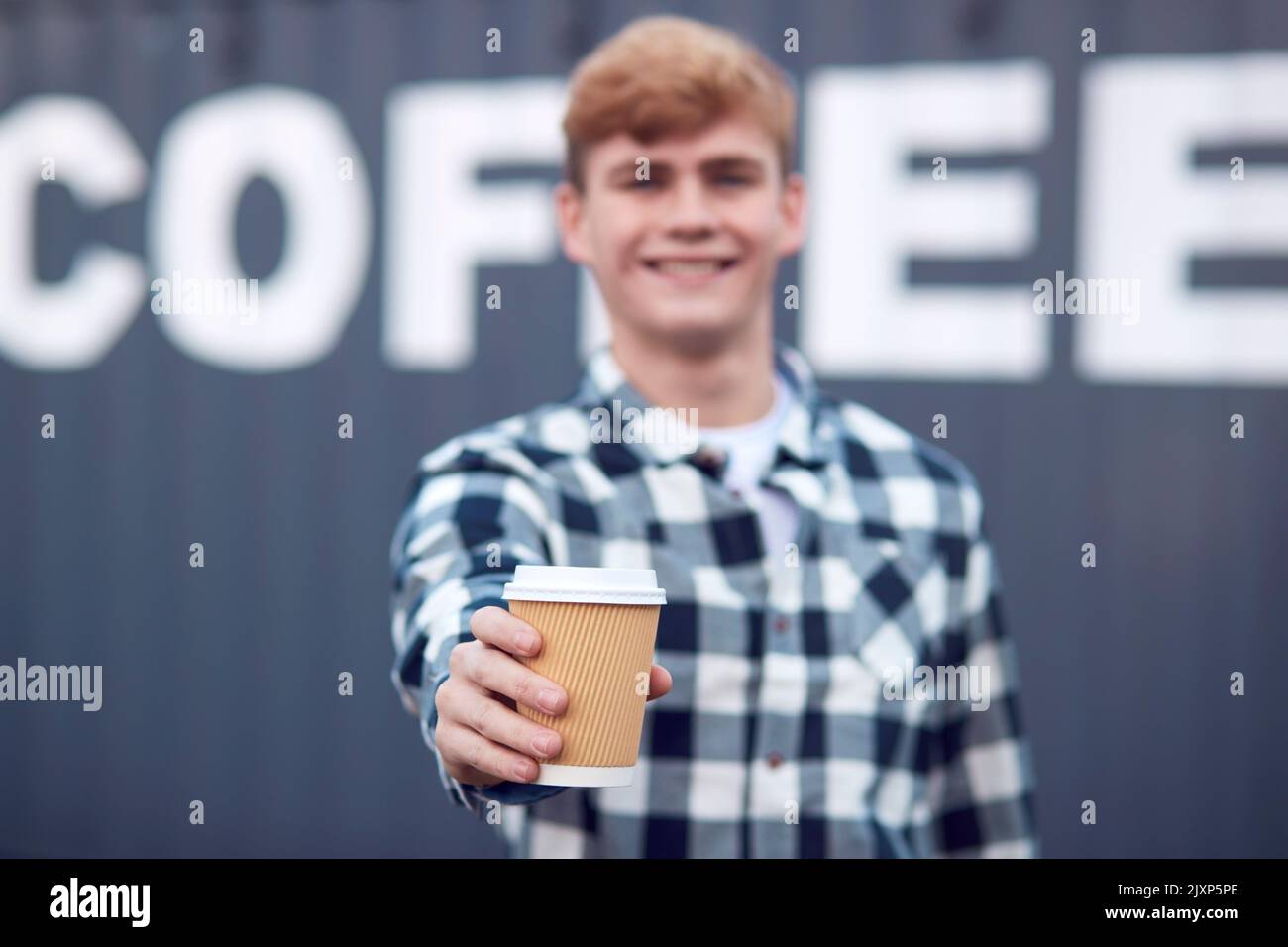 Male Worker Holding Takeaway Standing In Front Of Shipping Container Labelled Coffee Stock Photo