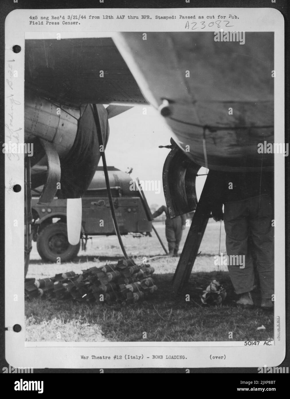 Clusters of fragmentation bombs are being loaded in the bomb bay of this B-25 Mitchell bomber while high octane gas is pumped into the tanks. Mitchells of the 12th AAF used these 'frags' with great effectiveness against German troop concentrations Stock Photo