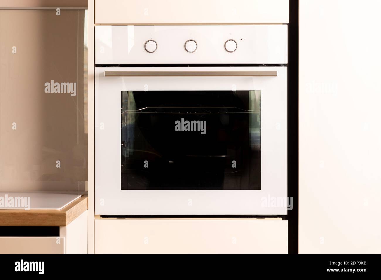 Modern bright white and beige kitchen with built-in oven closeup Stock Photo