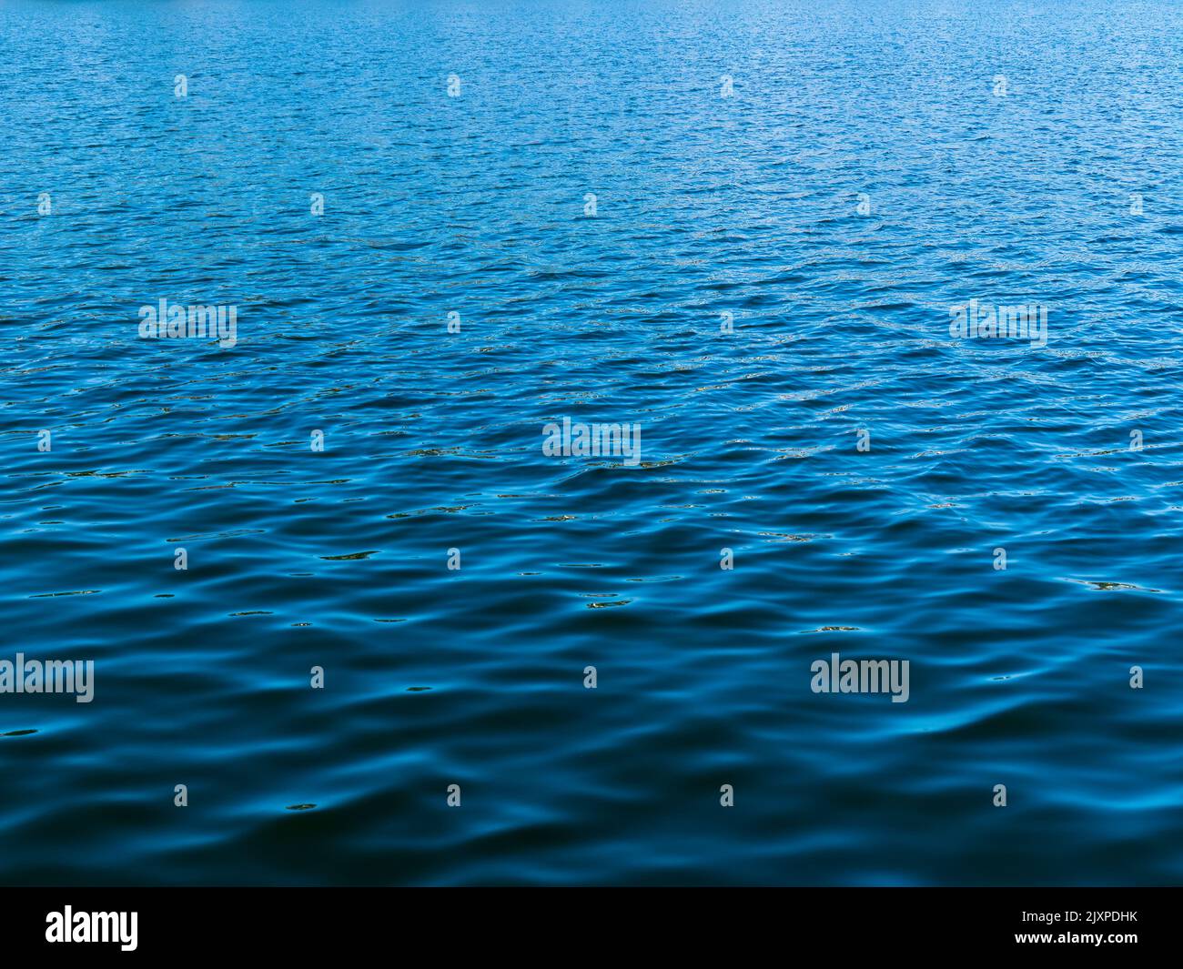 Waterlight light and dark blues ripple in diamond-shaped shapes across the harbor surface. Stock Photo