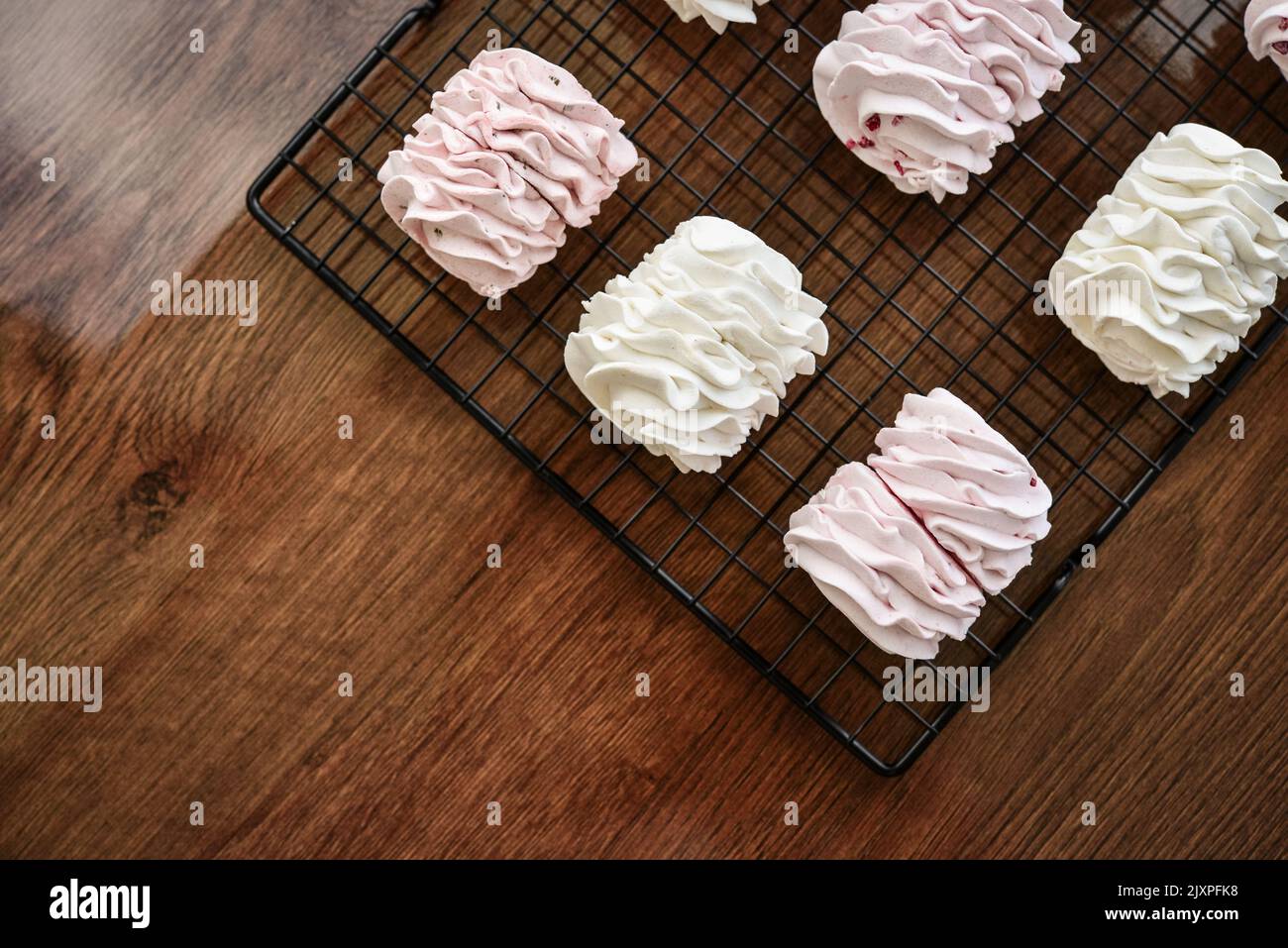 Cooling Rack with Homemade white and pink zephyr on wooden background, top view Stock Photo