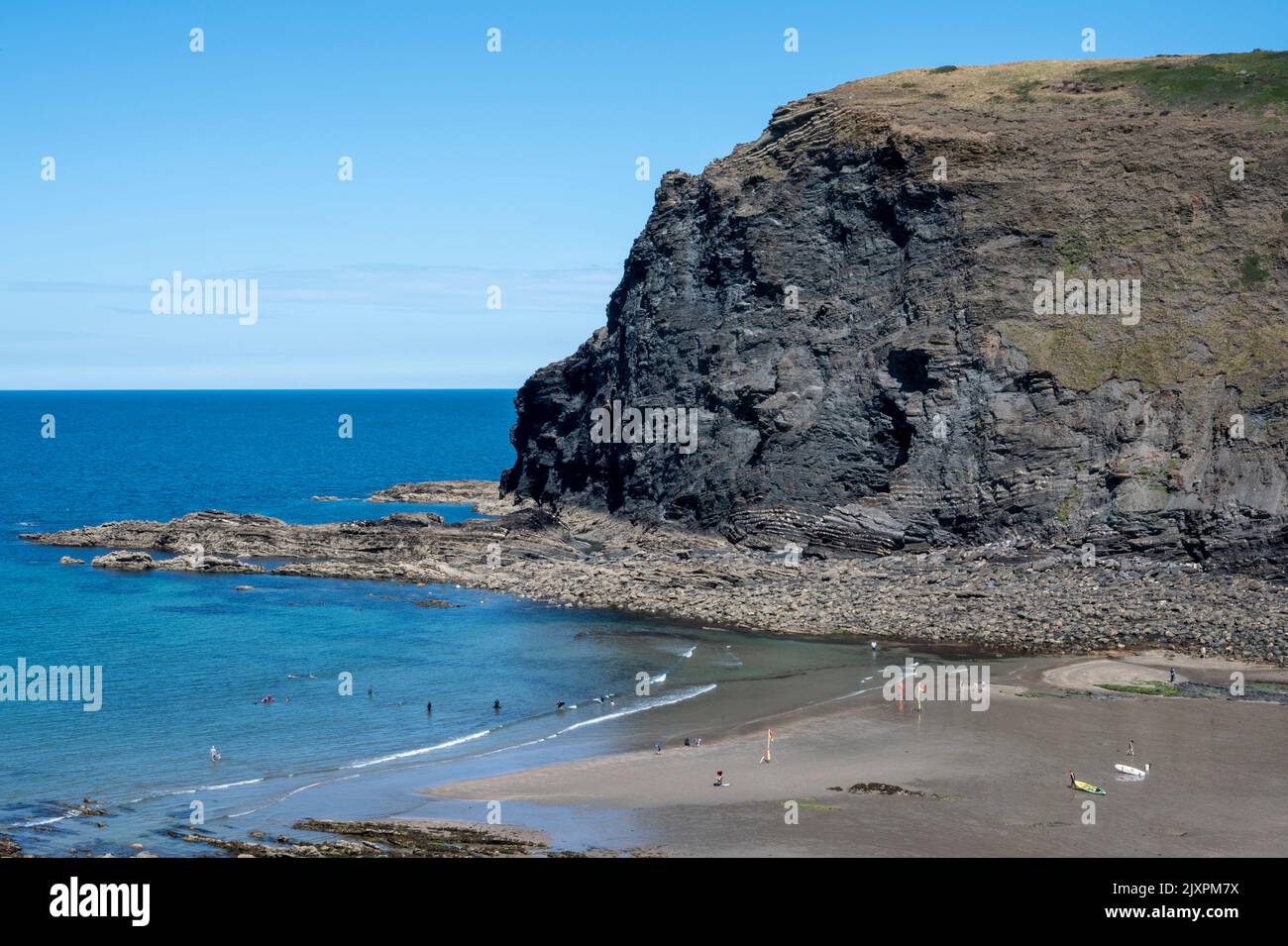 View of Crackington Haven Beach with holidaymakers enjoying the sun and sea. Stock Photo