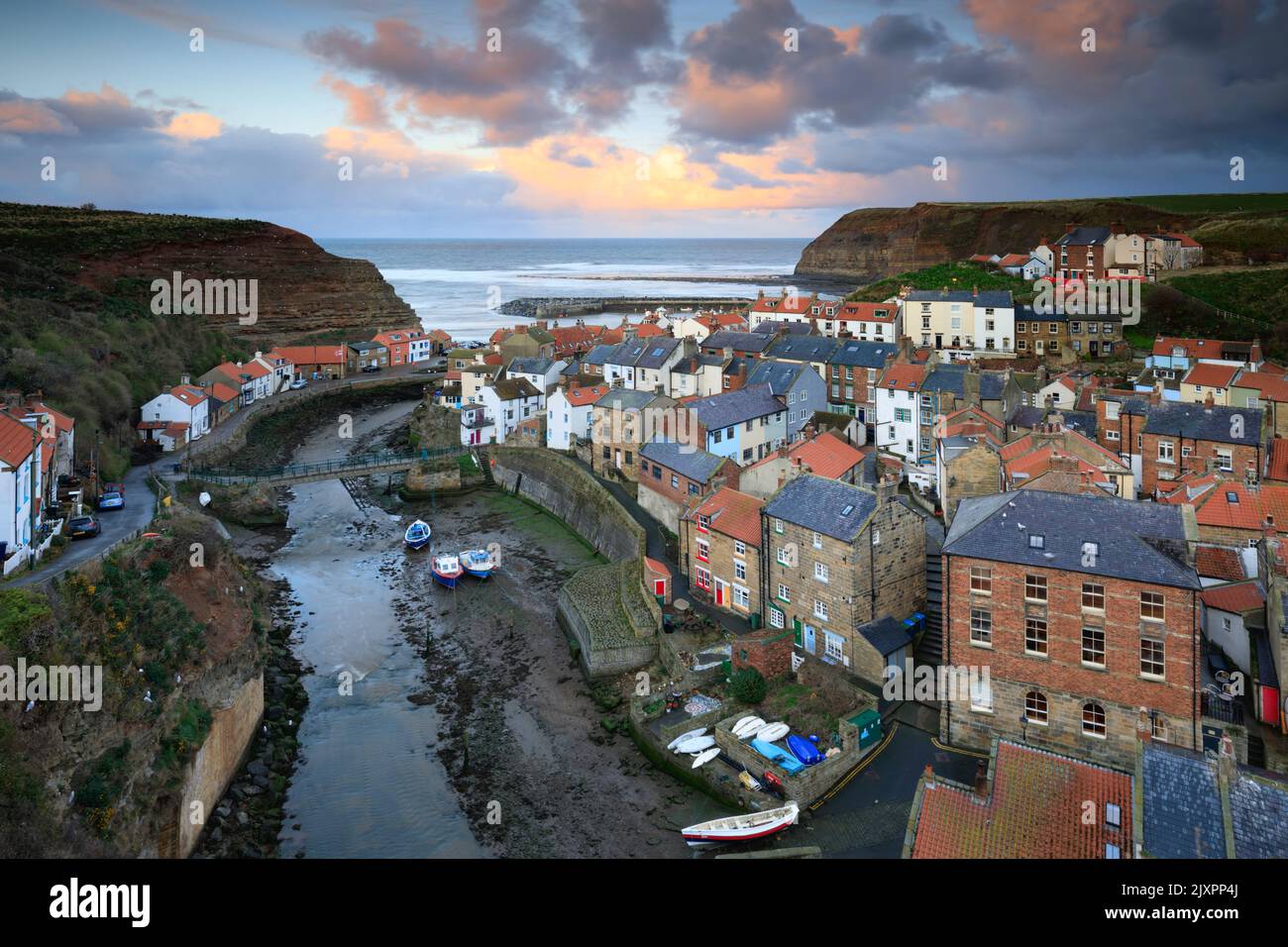 Clouds over the village of Staithes on the North Yorkshire Coast illuminated by the setting sun. Stock Photo