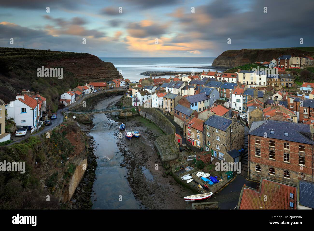 Clouds over the village of Staithes on the North Yorkshire Coast illuminated by the setting sun. Stock Photo