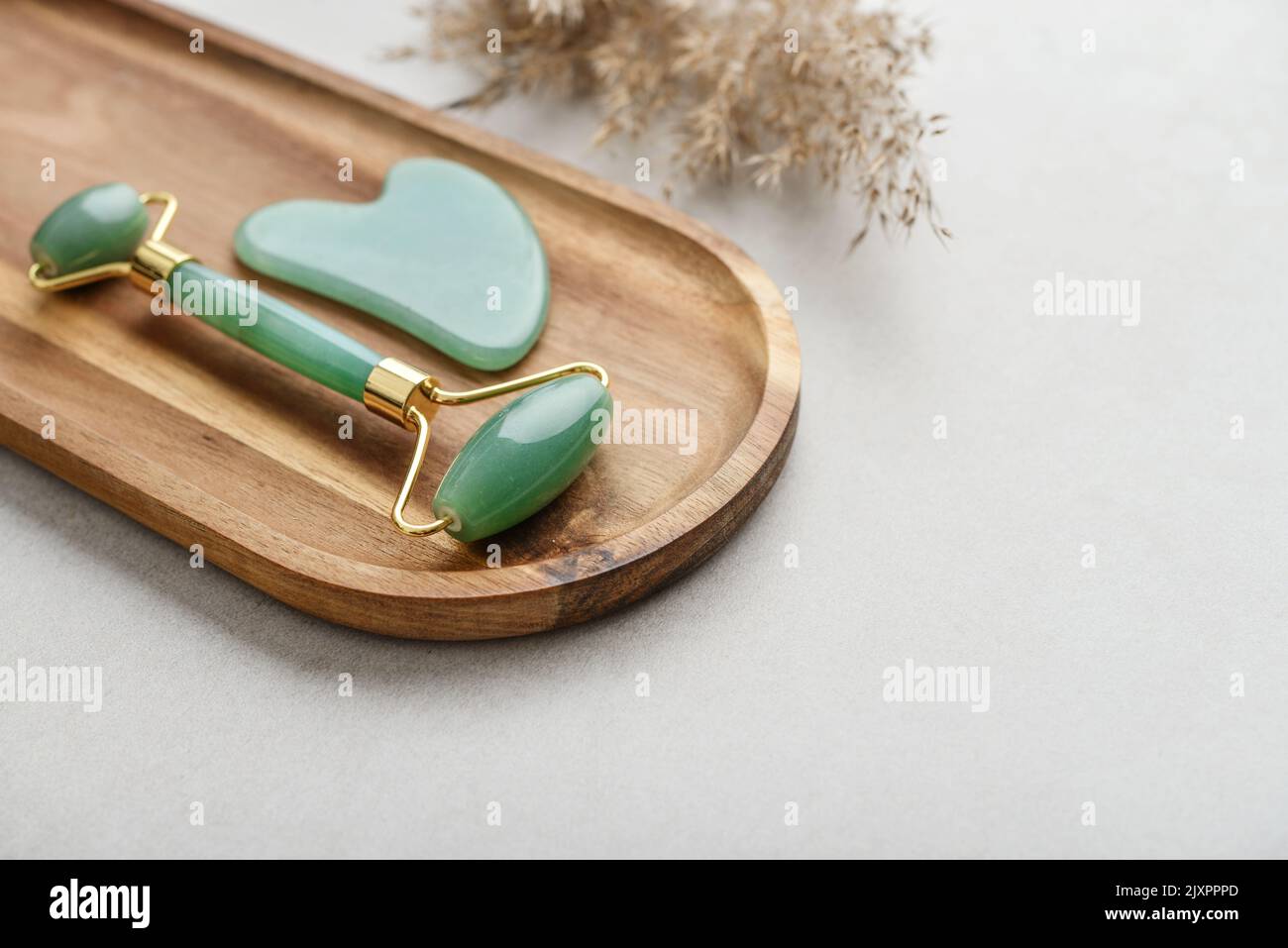 Facial jade massage rollers and gua sha massager made from natural jade stone on light concrete background, top view Stock Photo