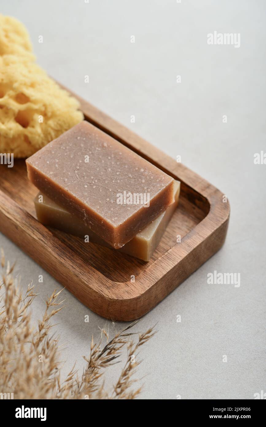 Natural soap bars and sponge on wooden tray with various toiletries on a light concrete background Stock Photo