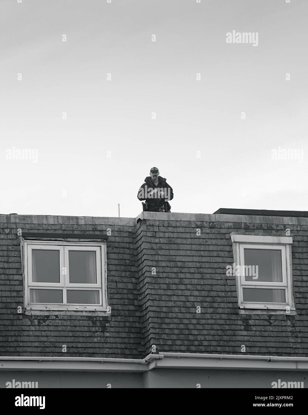 Armed Police Officer On A Rooftop With Binoculars During Surveillance Operations At Bournemouth Air Festival, UK Stock Photo