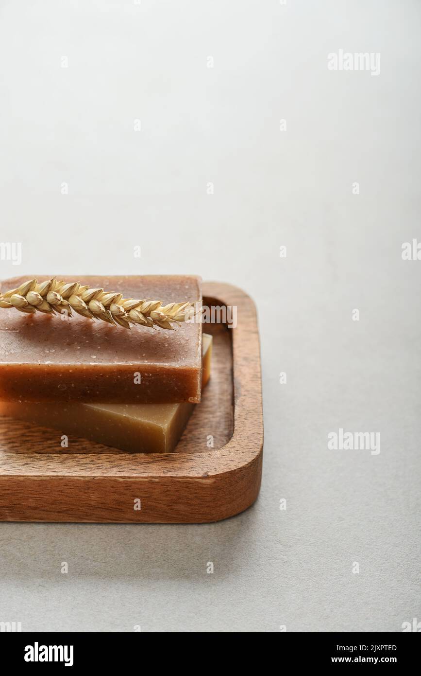 Natural handmade soap bars with wheat spikelet on wooden tray on a light concrete background Stock Photo