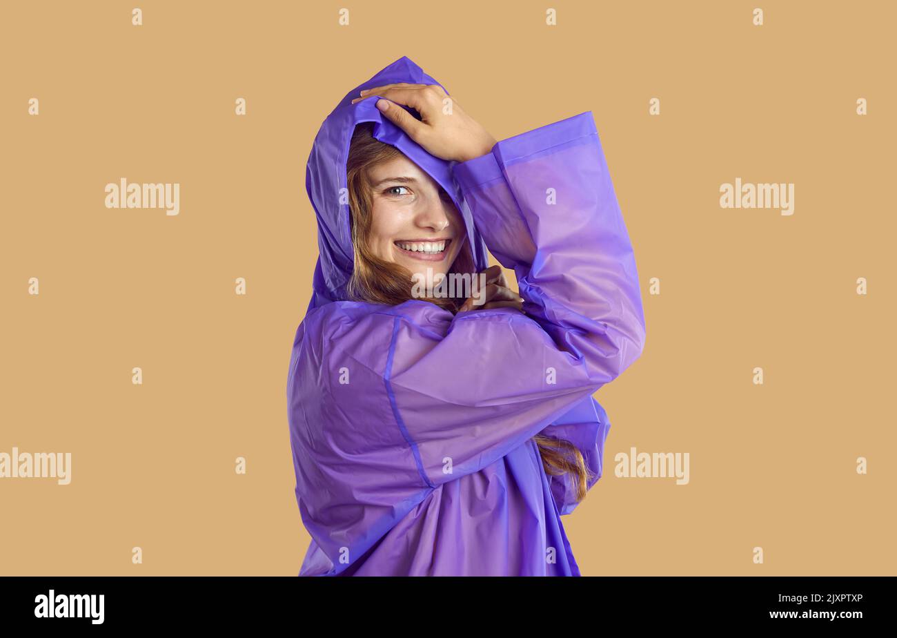 Portrait of beautiful and playful young woman who is wearing raincoat with hood. Stock Photo
