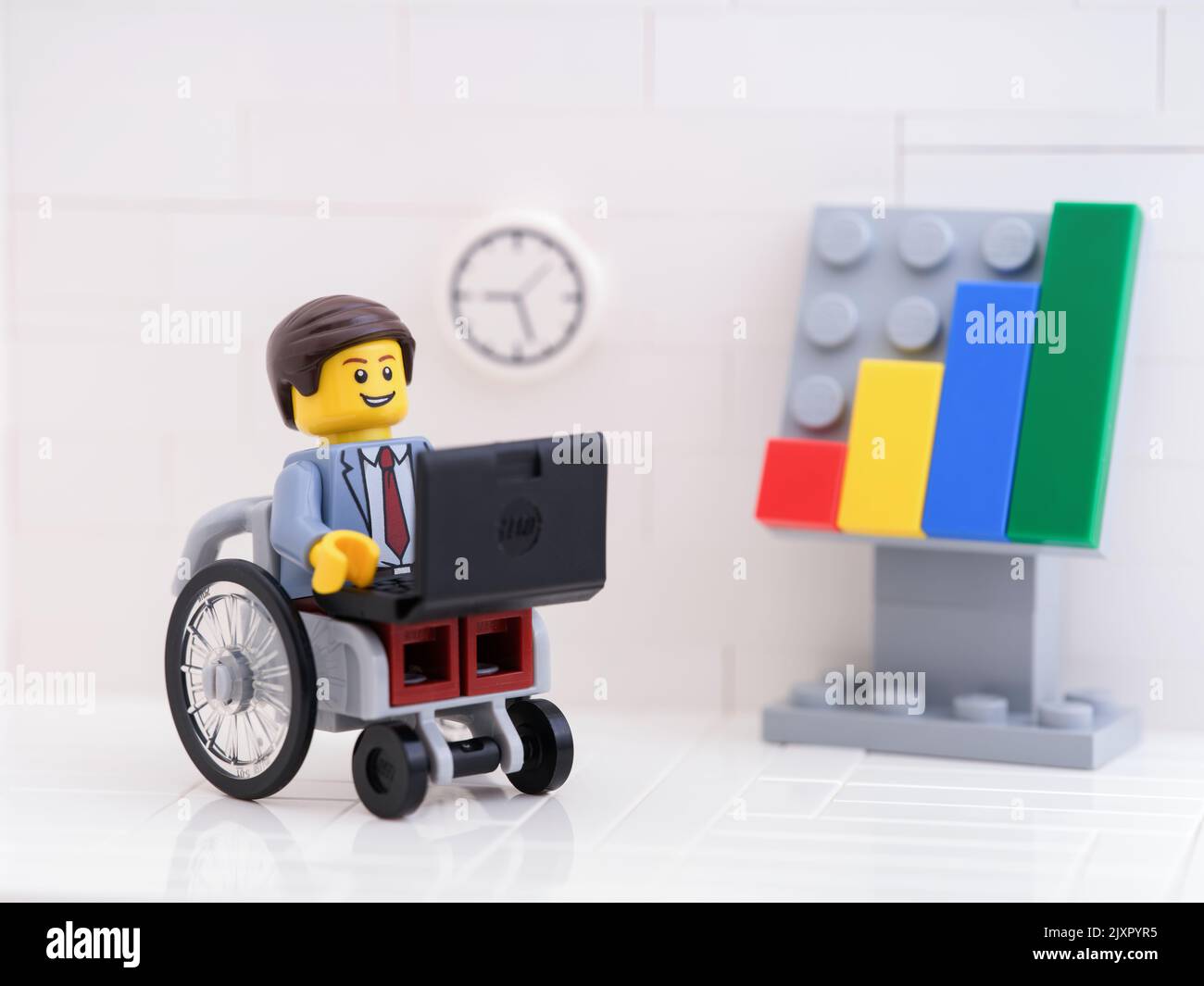 Tambov, Russian Federation - September 6, 2022 A Lego businessman minifigure in a wheelchair using a laptop in his office. Stock Photo