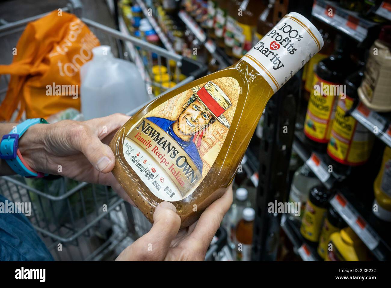 A shopper chooses a bottle of Newman's Own salad dressing in a