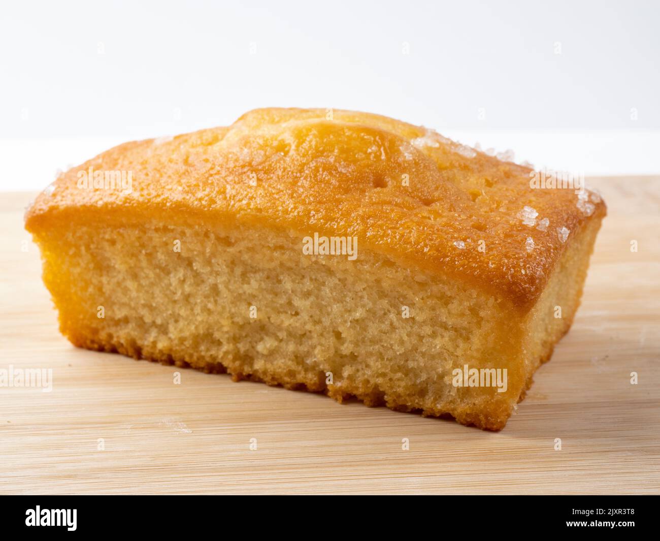 Lemon drizzle  loaf tin cake isolated on a bamboo board Stock Photo