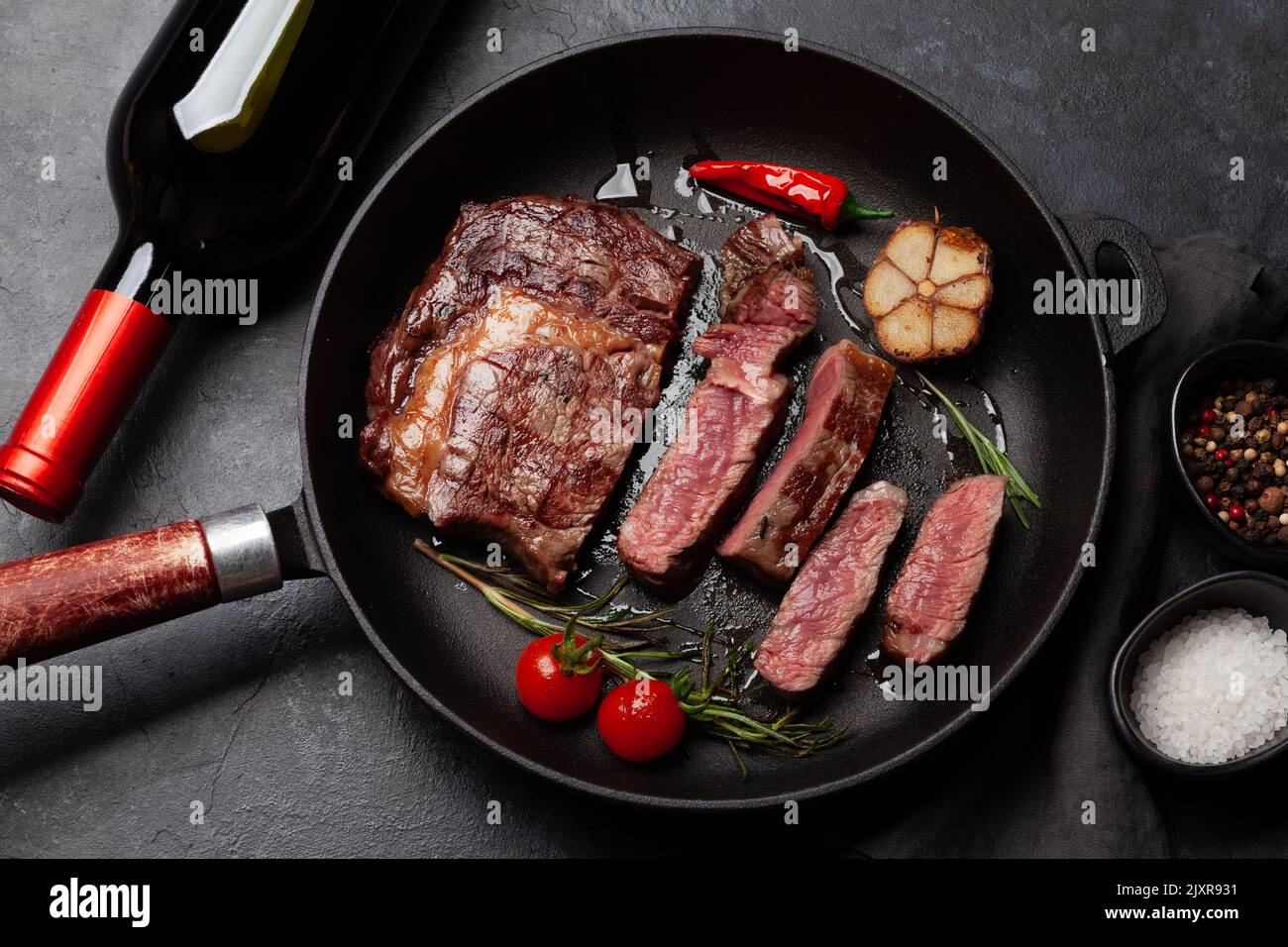 Grilled ribeye beef steak in frying pan with herbs and spices. Flat lay