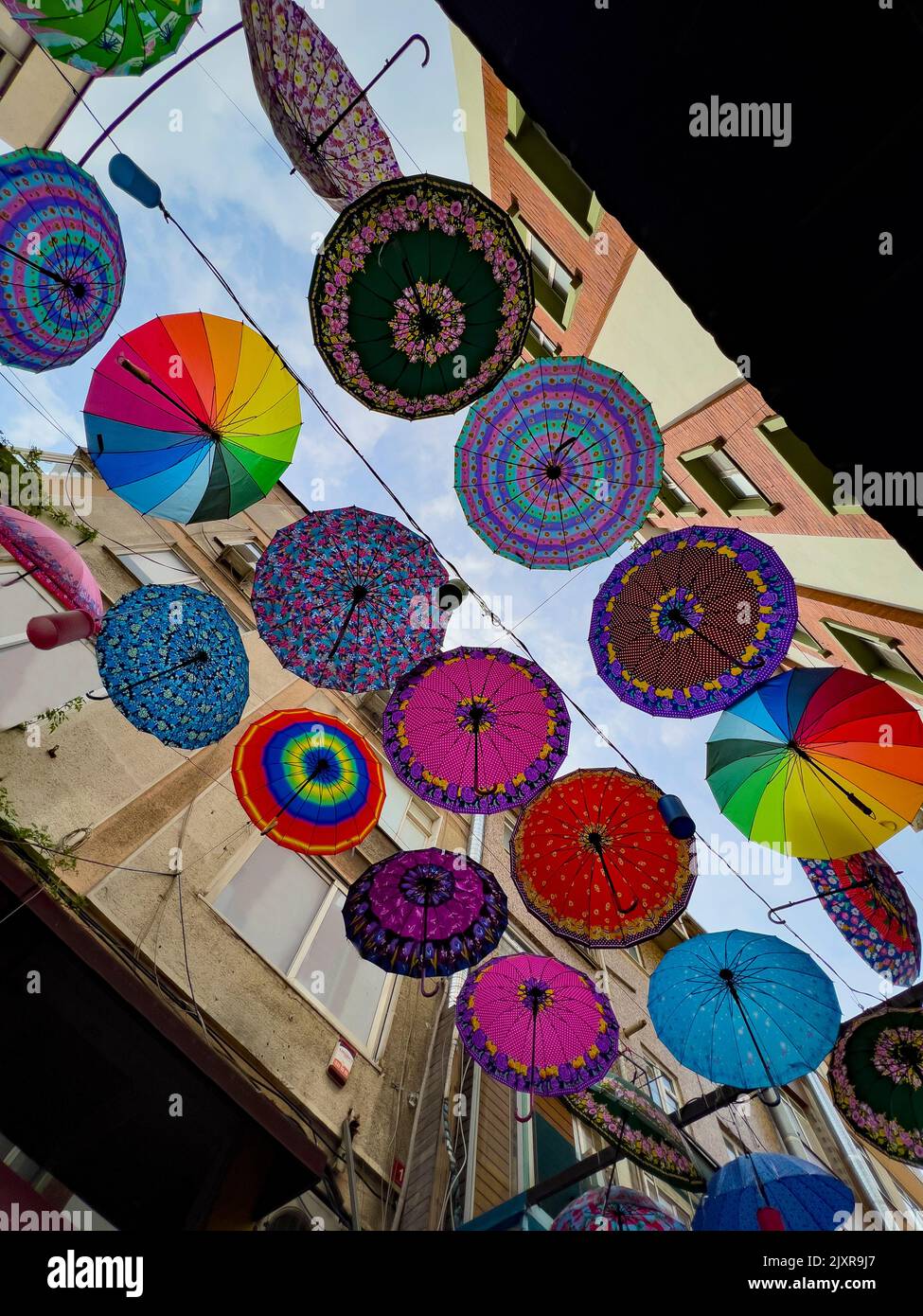 Colorful hanging umbrellas in various designs and shapes hanging between residential apartments in a district in Istanbul, Turkey, directly above. Stock Photo