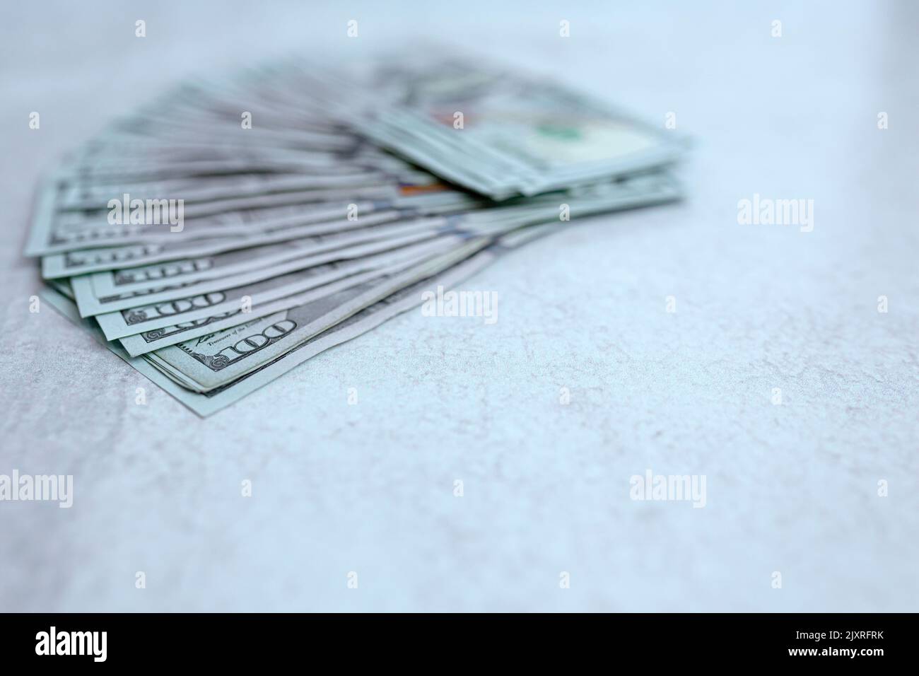 a large fanned out stack of United States hundred dollar bills on a gray background with copy space for a banner. Stock Photo