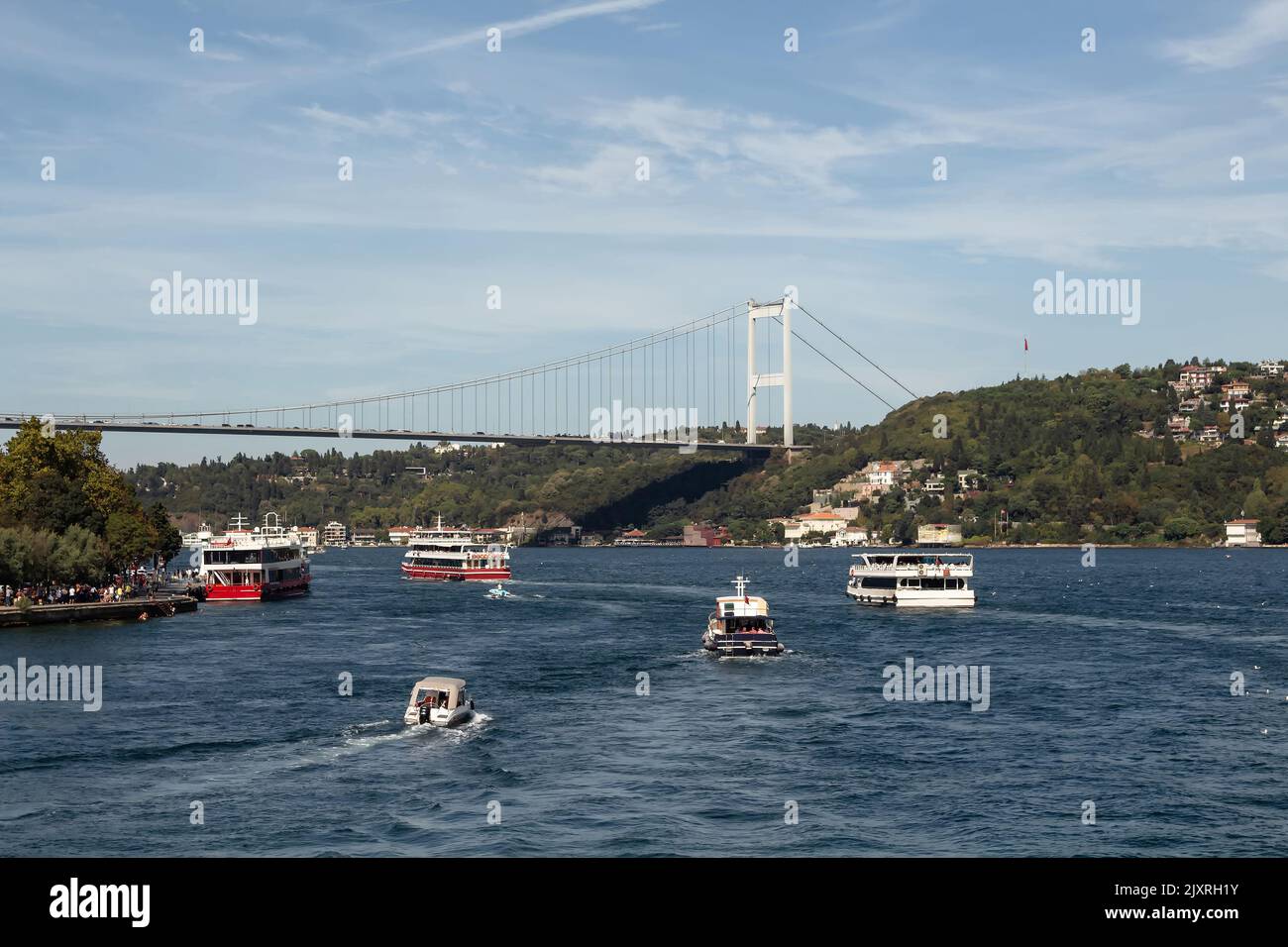 View of cruise tour boats passing on Bosphorus and FSM bridge in Istanbul. It is a sunny summer day. Beautiful travel scene. Stock Photo