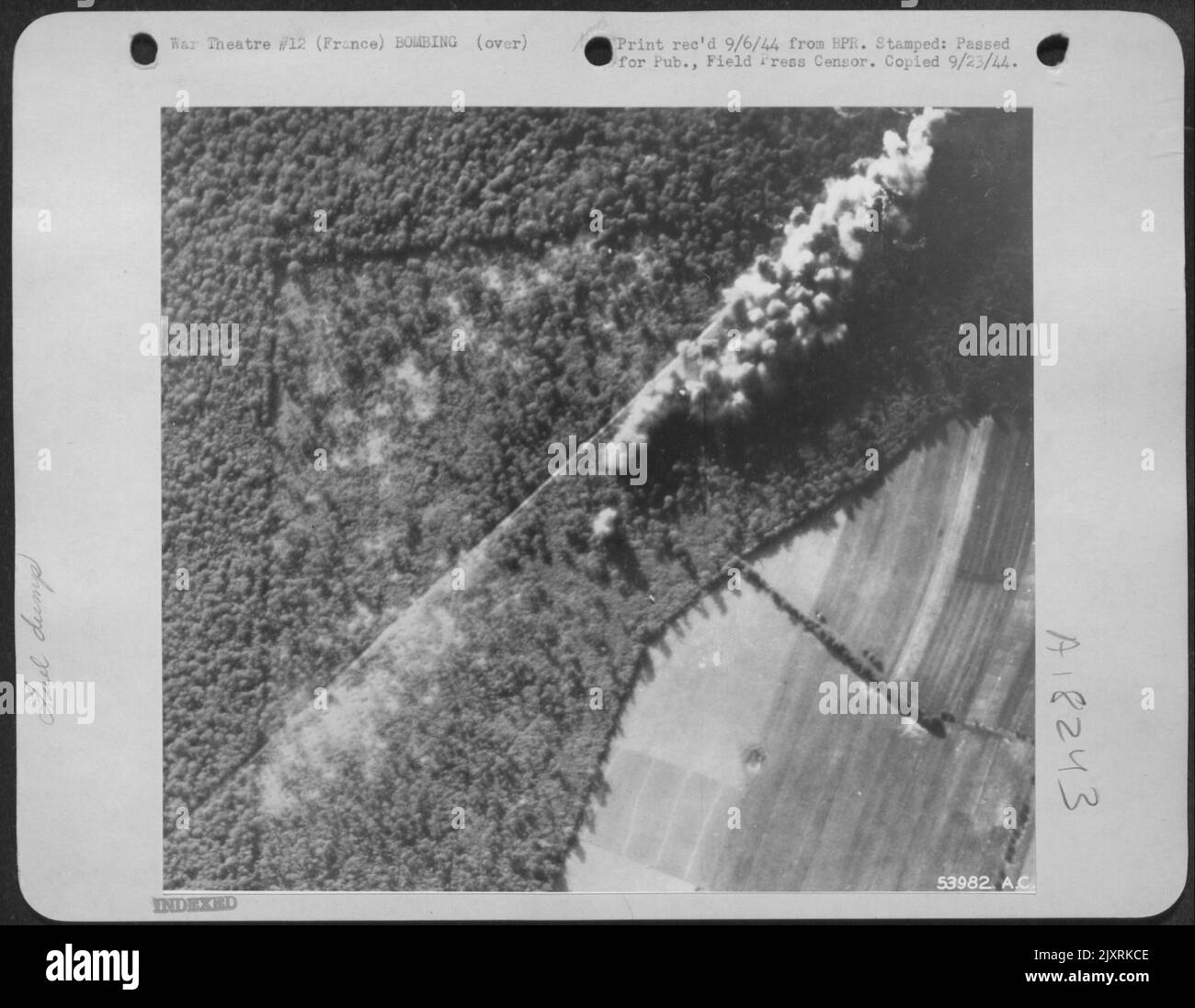 FRANCE-9th Air Force crews which bombed the fuel dump in the thickly wooded forest de Conches, hit a narrow strip of forest bordering the concrete road. The dump was attacked many times, and each time the airmen saw telltale black smoke Stock Photo