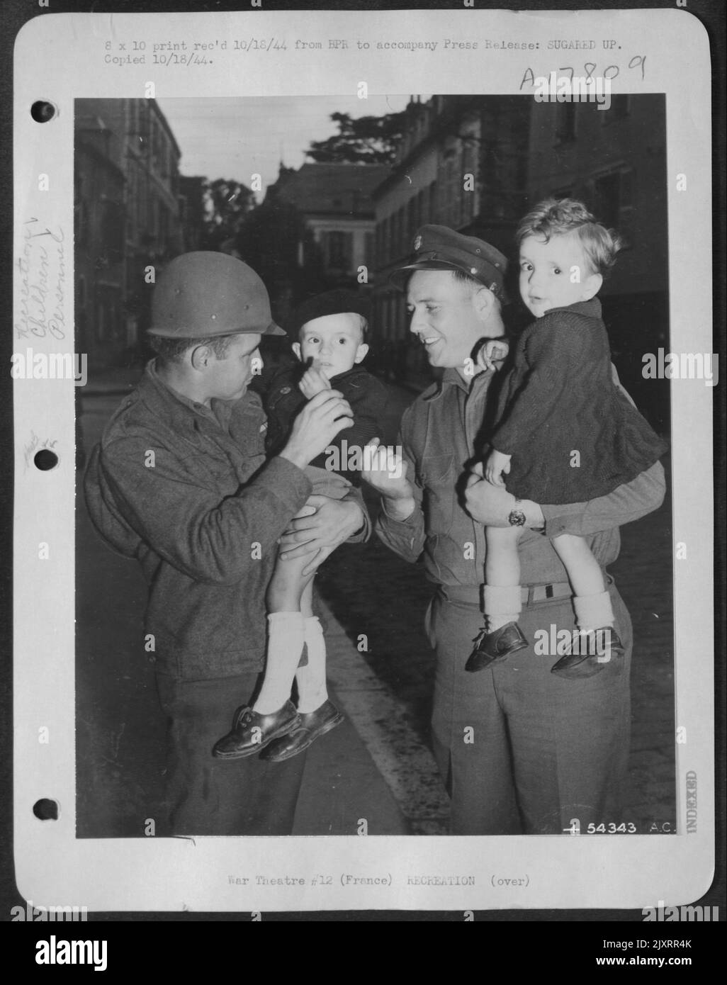 FRANCE-Sgts Jim Swarts, Jr., (left), Kansas City, Mo., and James Beggs, Clarksville, Tex., of a U.S. Army 9th Air Force Martin B-26 Marauder group can't talk French so substituted candy for conversation. These friendly expressions resulted. Stock Photo
