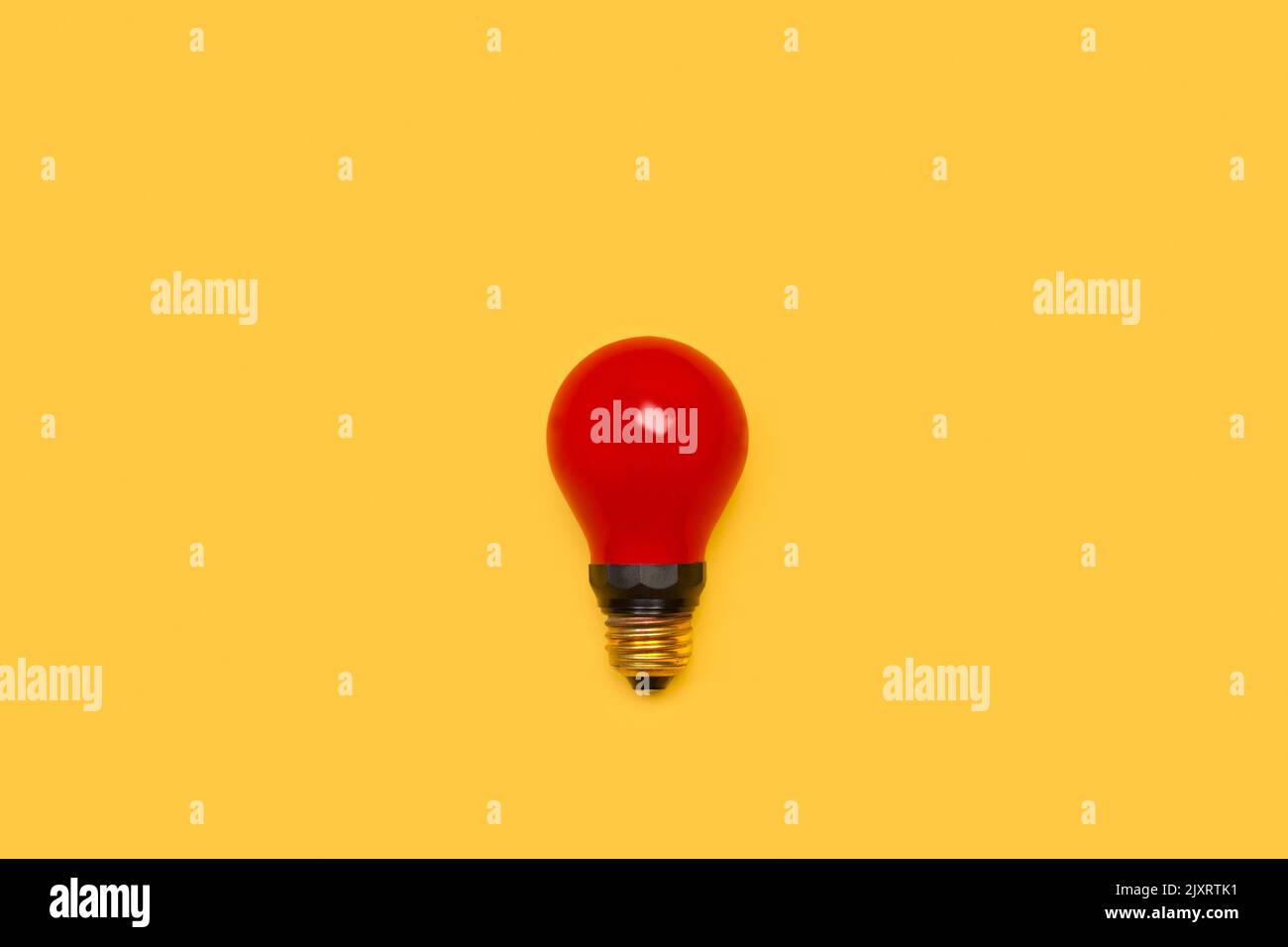 A red lightbulb on a yellow background with copy space Stock Photo