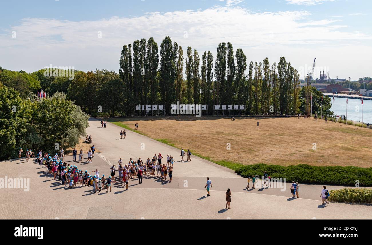 A picture of the Polish sign that reads as 'No More War' in Westerplatte, next to a group of children on a field trip. Stock Photo