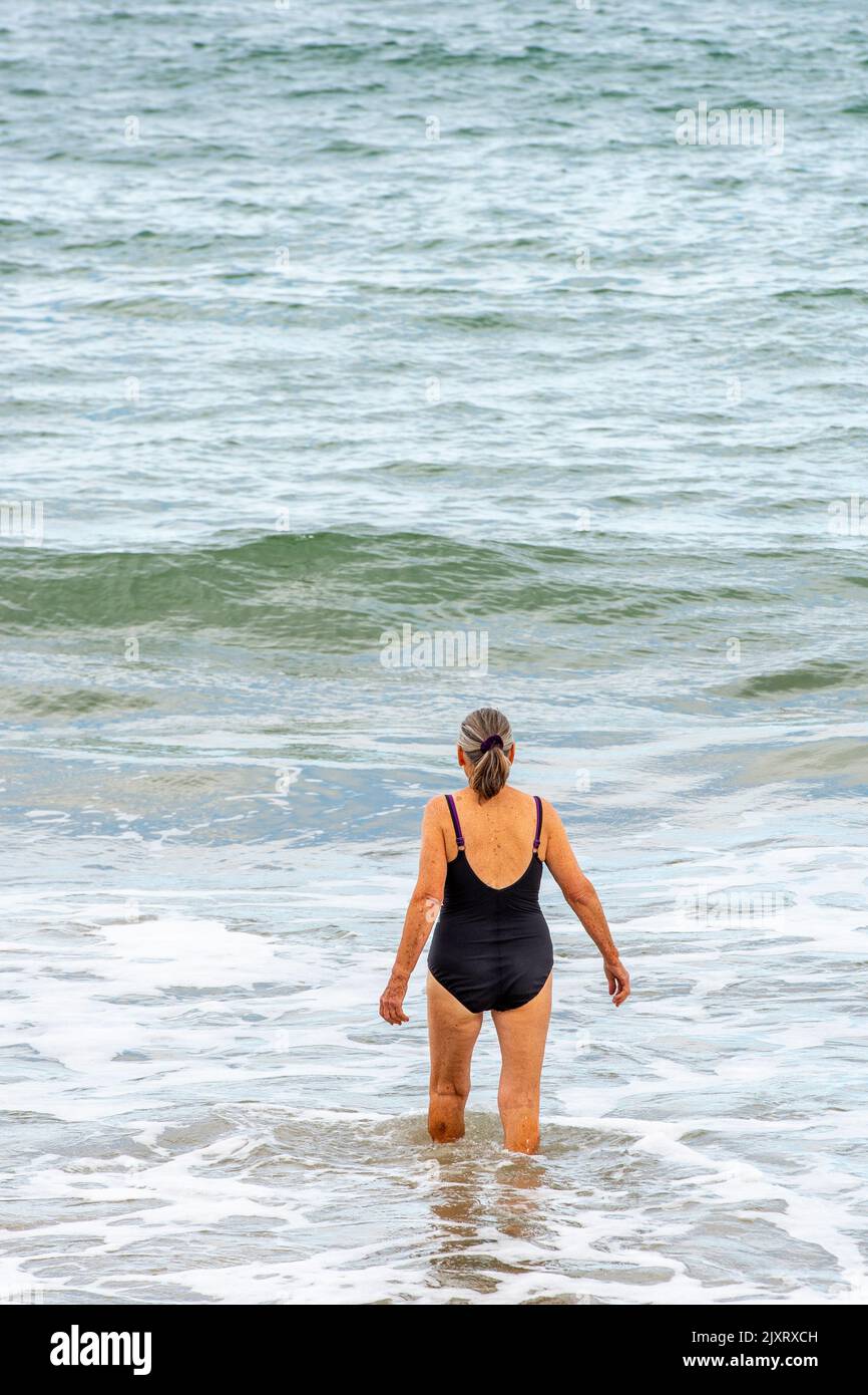 older lady wild swimming in the sea, older lady having a dip in the sea, lady wearing black swimming costume wild swimming, female wild swimmer in sea Stock Photo