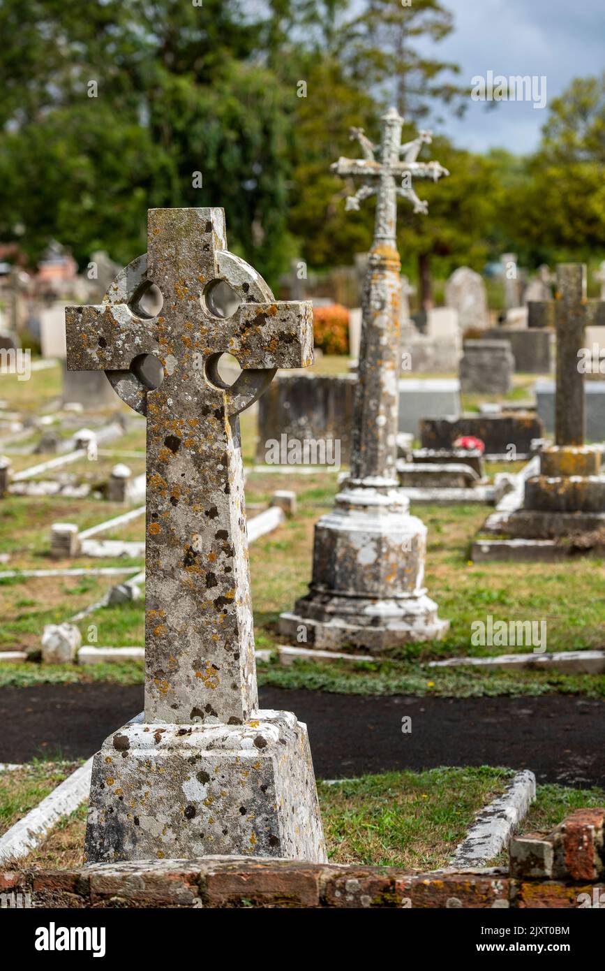 celtic cross gravestone and other graves in a cemetery on the isle of