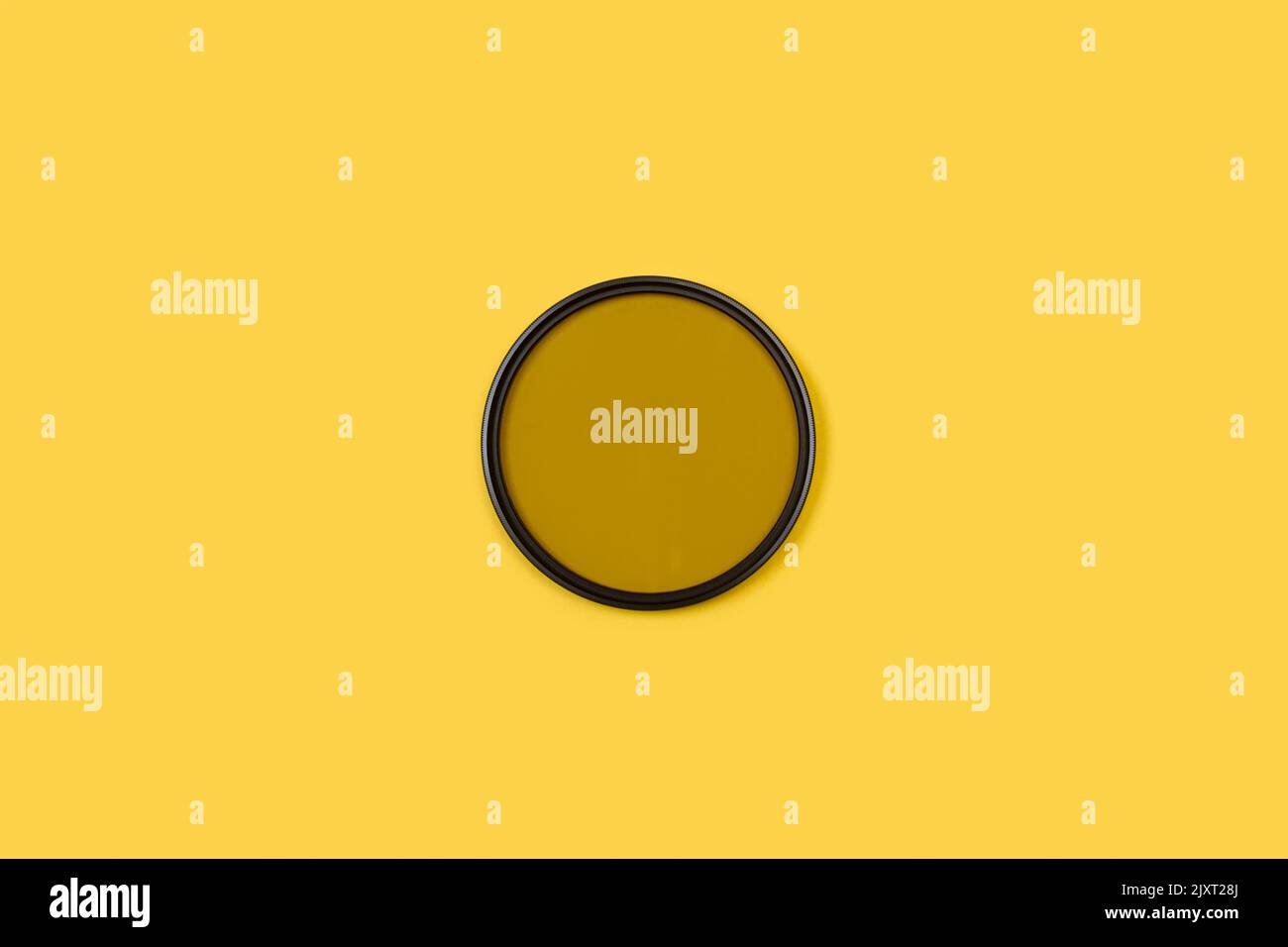A photography polarizing filter on a yellow background with copy space Stock Photo