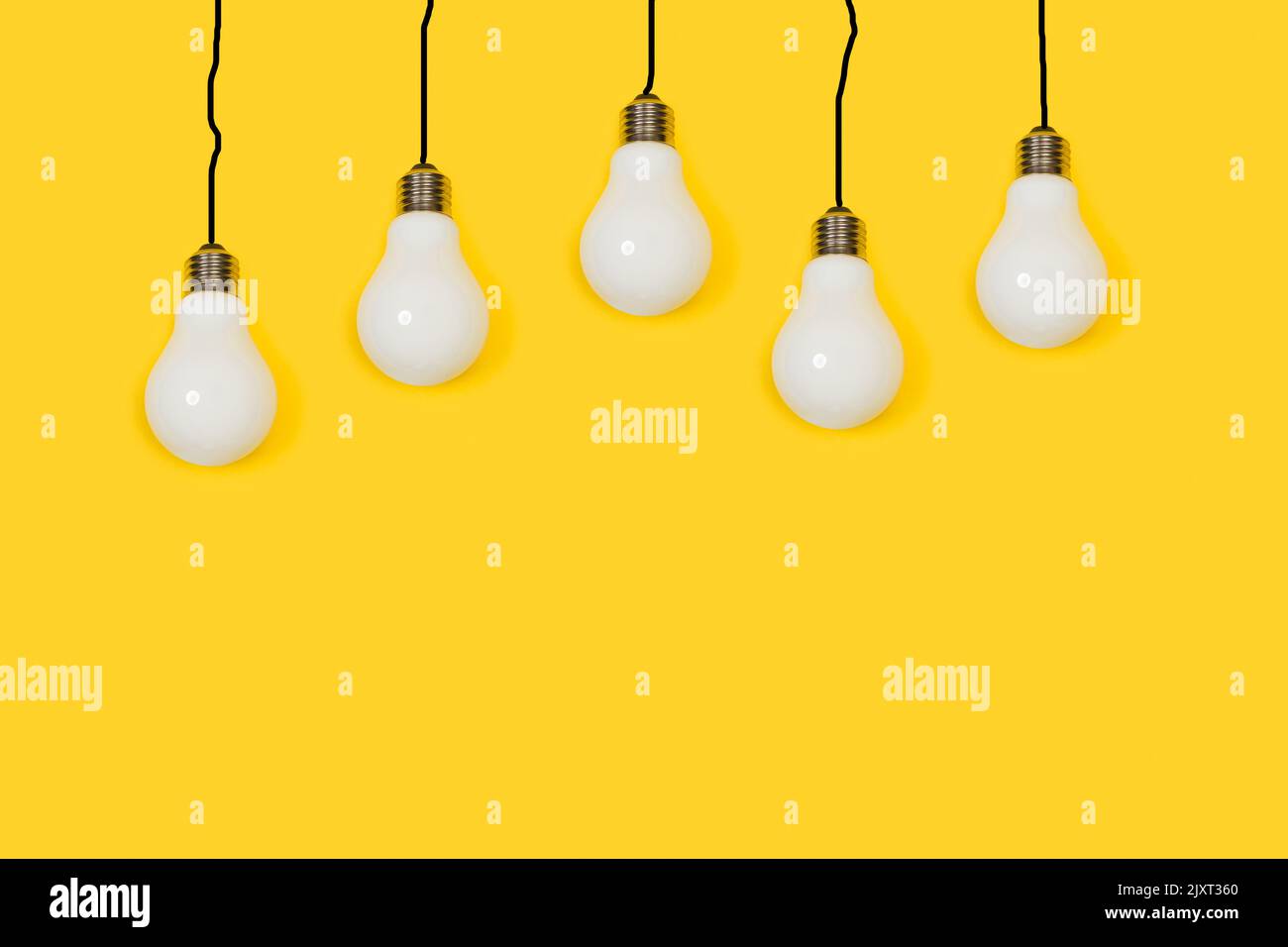 Lightbulbs hanging from black lines cable shape on a yellow background ...
