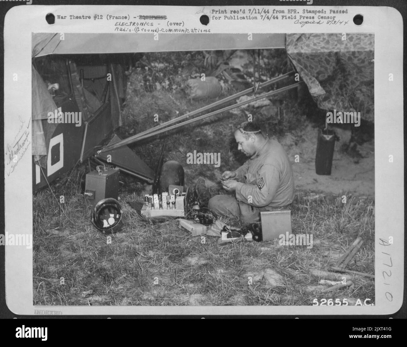 Photographed by a 9th AF Combat Cameraman, Sgt. William N. Stehle of Perry, Mo., a radio repair man for the artillery, works on the radio from one of the small planes used in spotting targets and fire effectiveness for the ground forces. Stock Photo